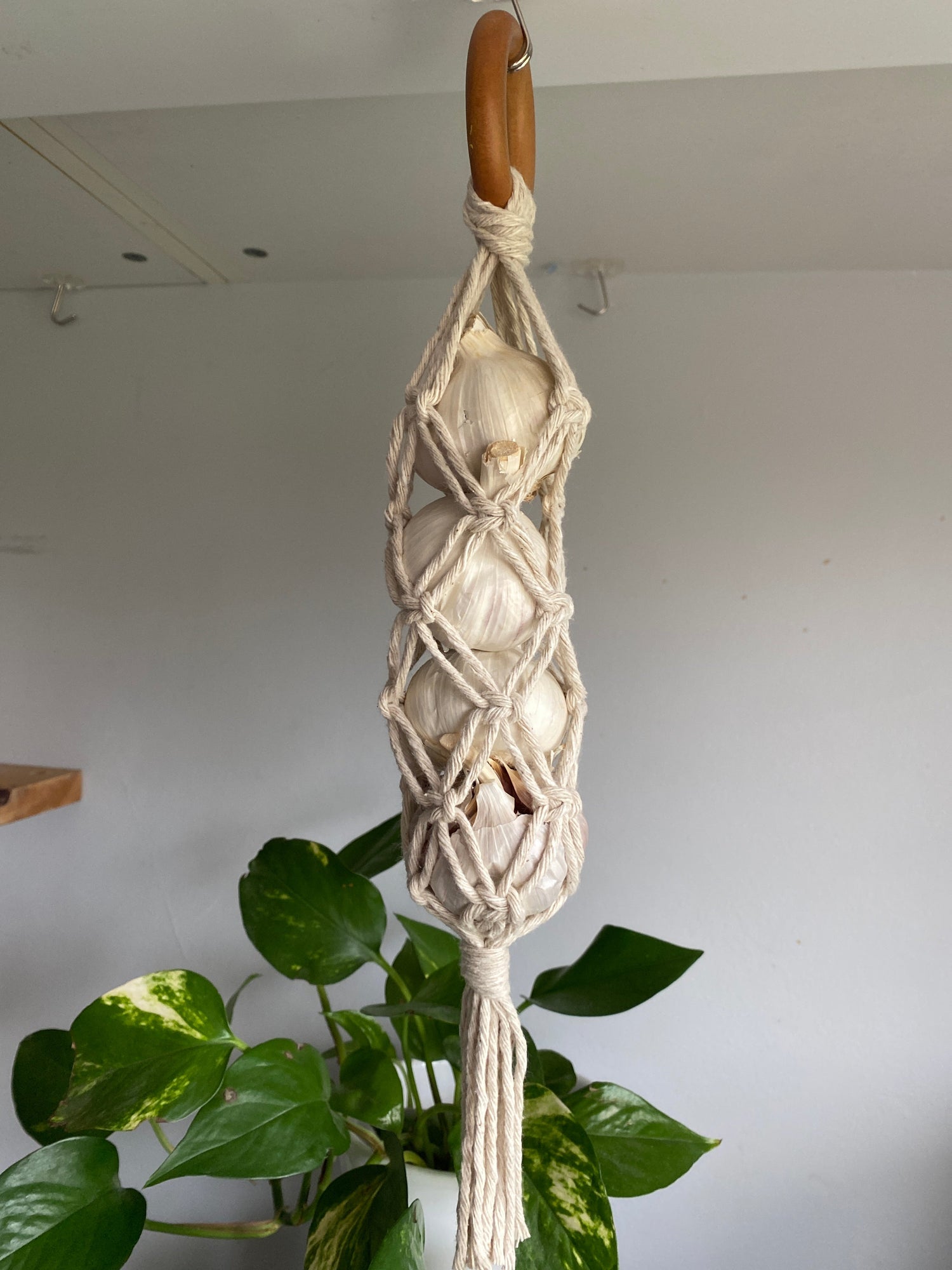 Handmade garlic storage hanger made with recycled cotton on a repurposed wooden hanging ring