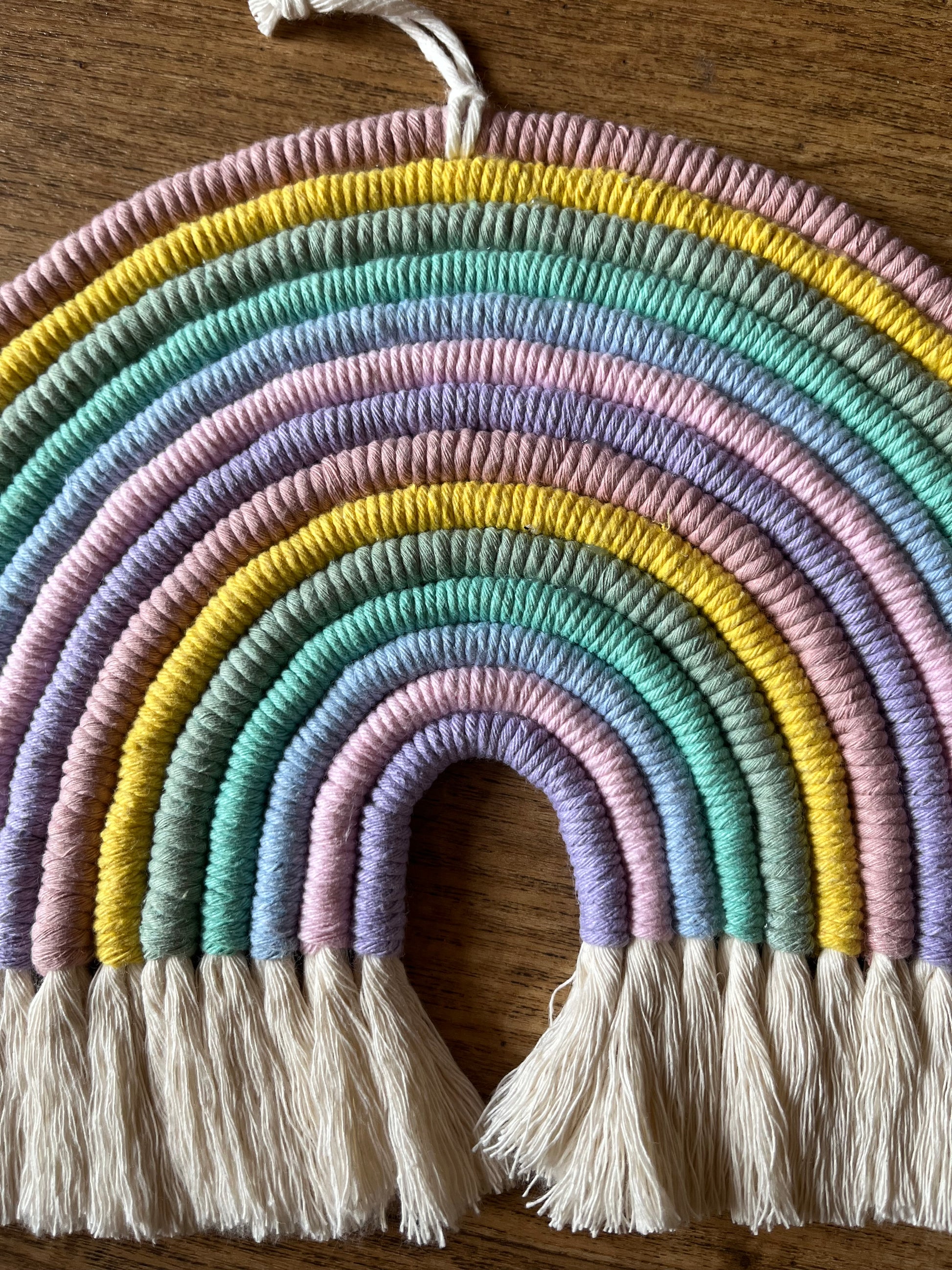 Handmade macrame rainbow wall hanging made with recycled cotton in pastel colours