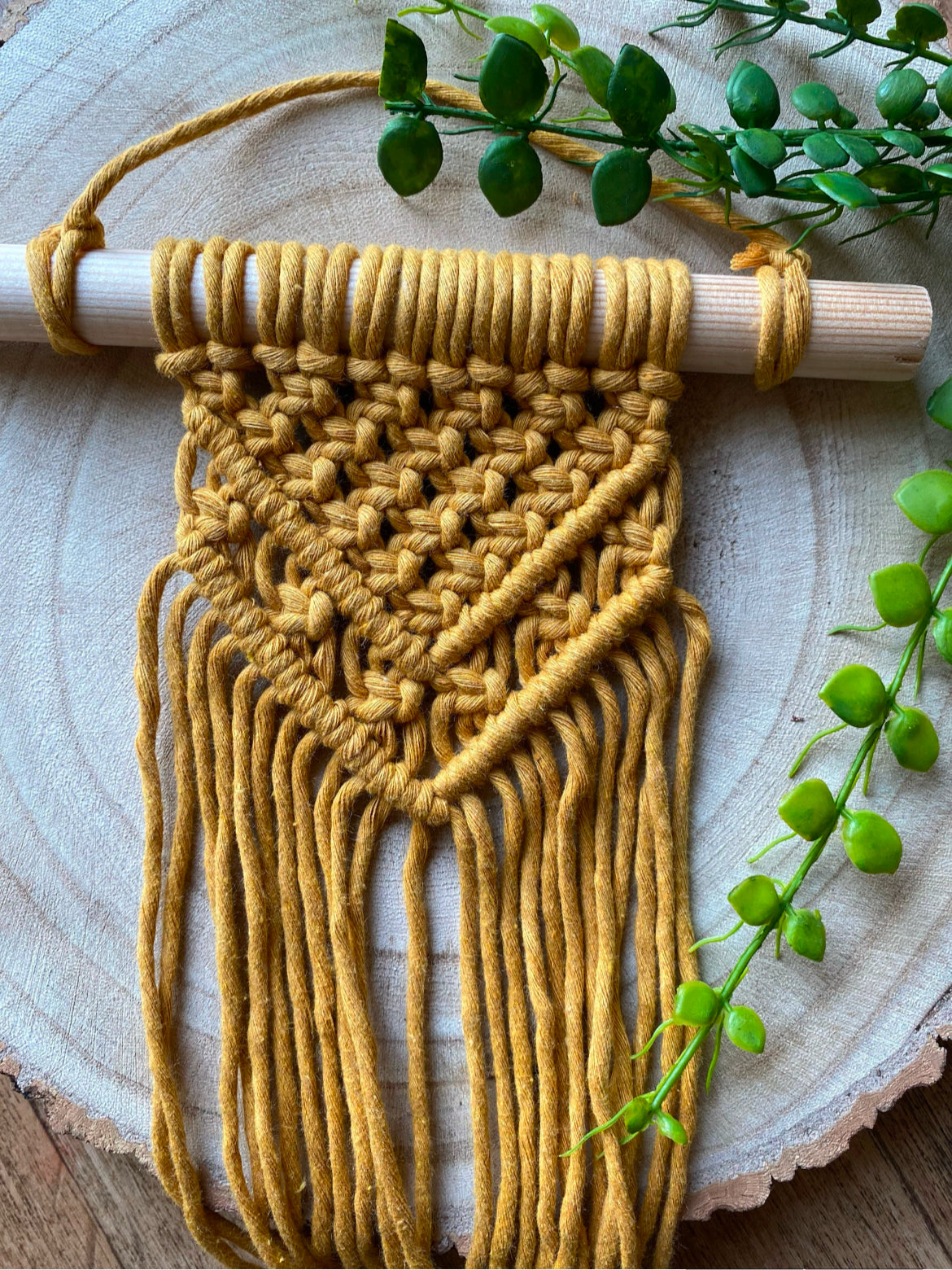 Handmade macrame wall hanging made with mustard yellow recycled cotton yarn on a solid wooden dowel.