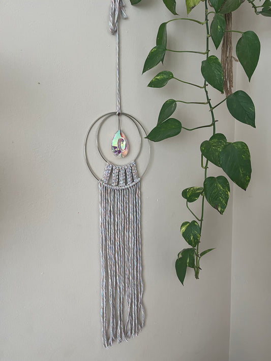 Handmade macrame Suncatcher made with pastel coloured recycled yarn, on two metal hoops, with a large hanging crystal in the centre.