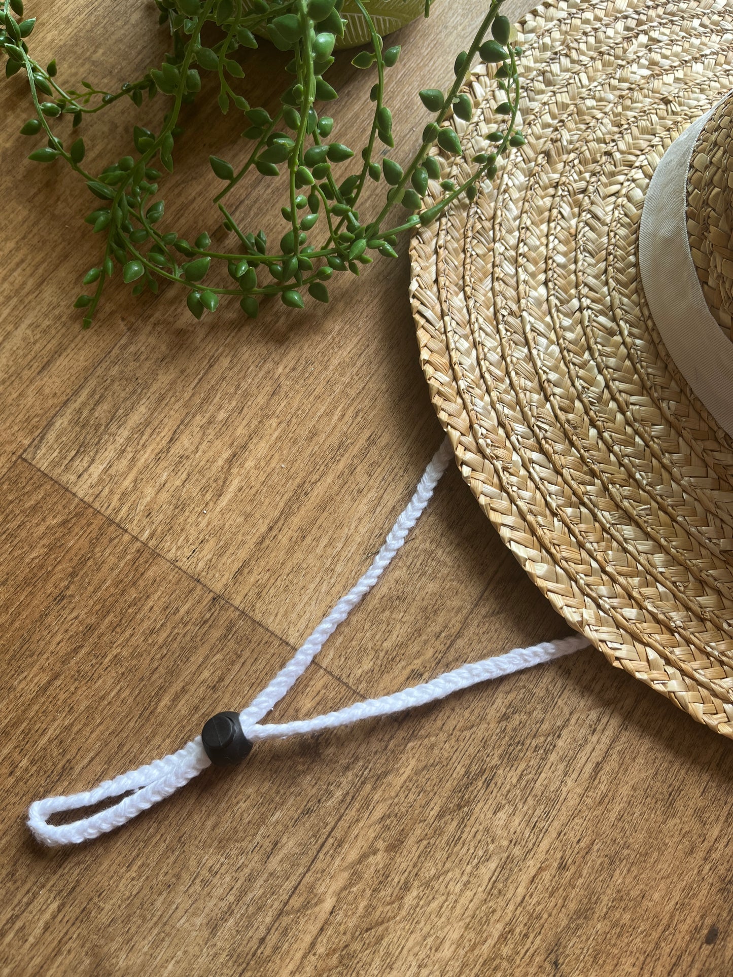 Straw hat with a white strap on a wooden surface