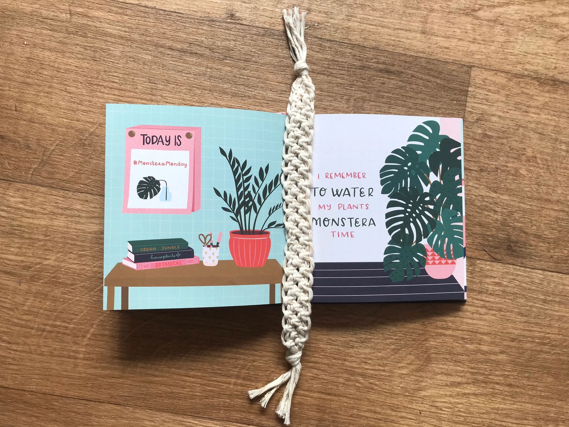 Handmade macramé bookmark with knotted design made with golden natural recycled cotton, laid across an open hardback book about plants, on a wooden surface.