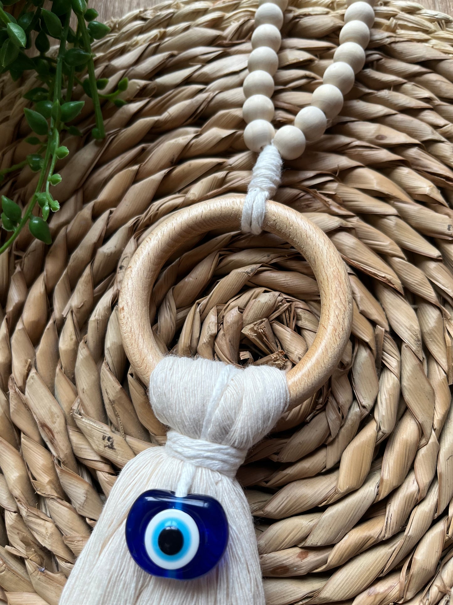 Handmade macrame door hanger, made with recycled cotton, on a wooden ring, with a blue resin evil eye bead.
