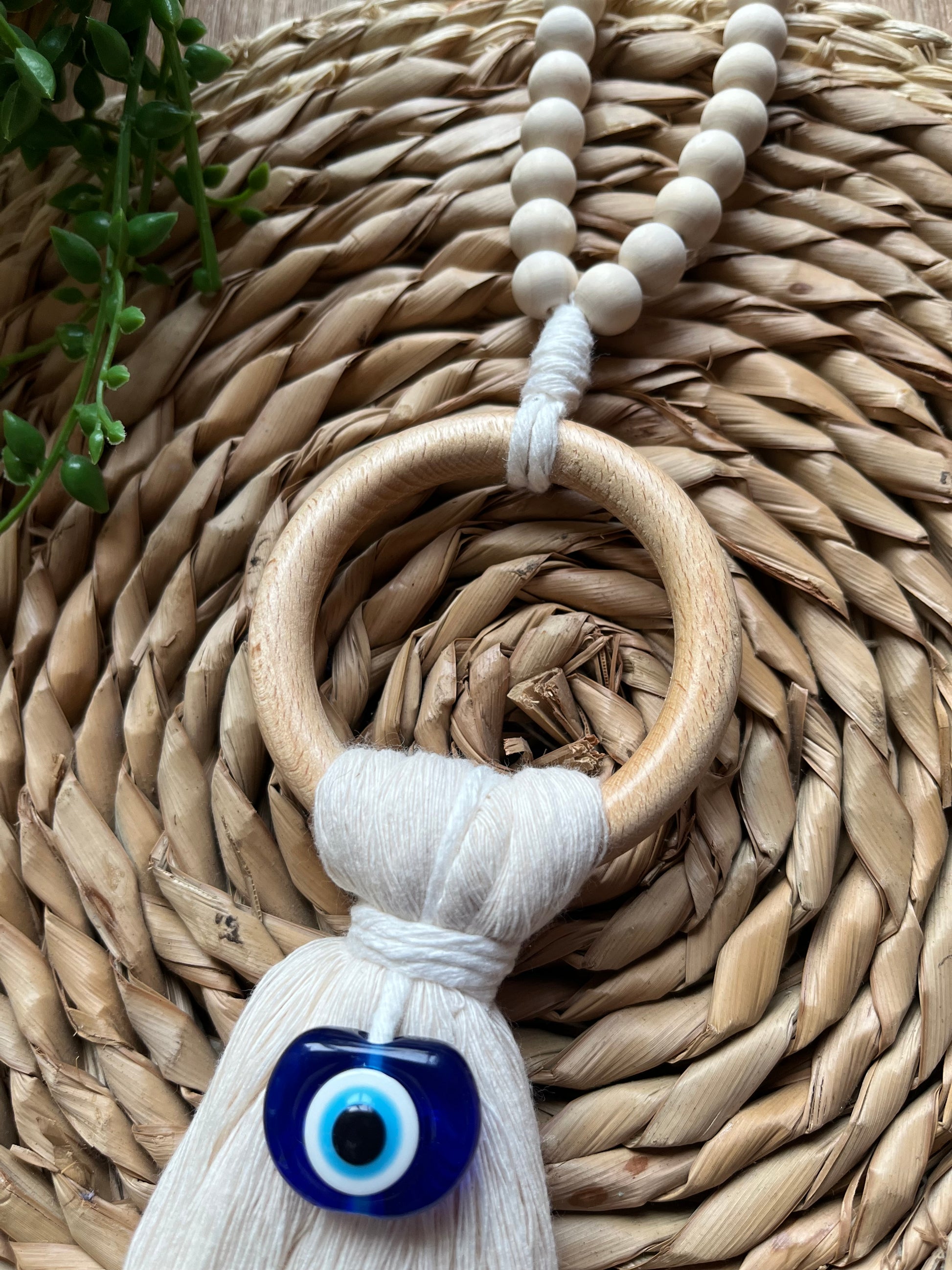 Handmade macrame door hanger, made with recycled cotton, on a wooden ring, with a blue resin evil eye bead.