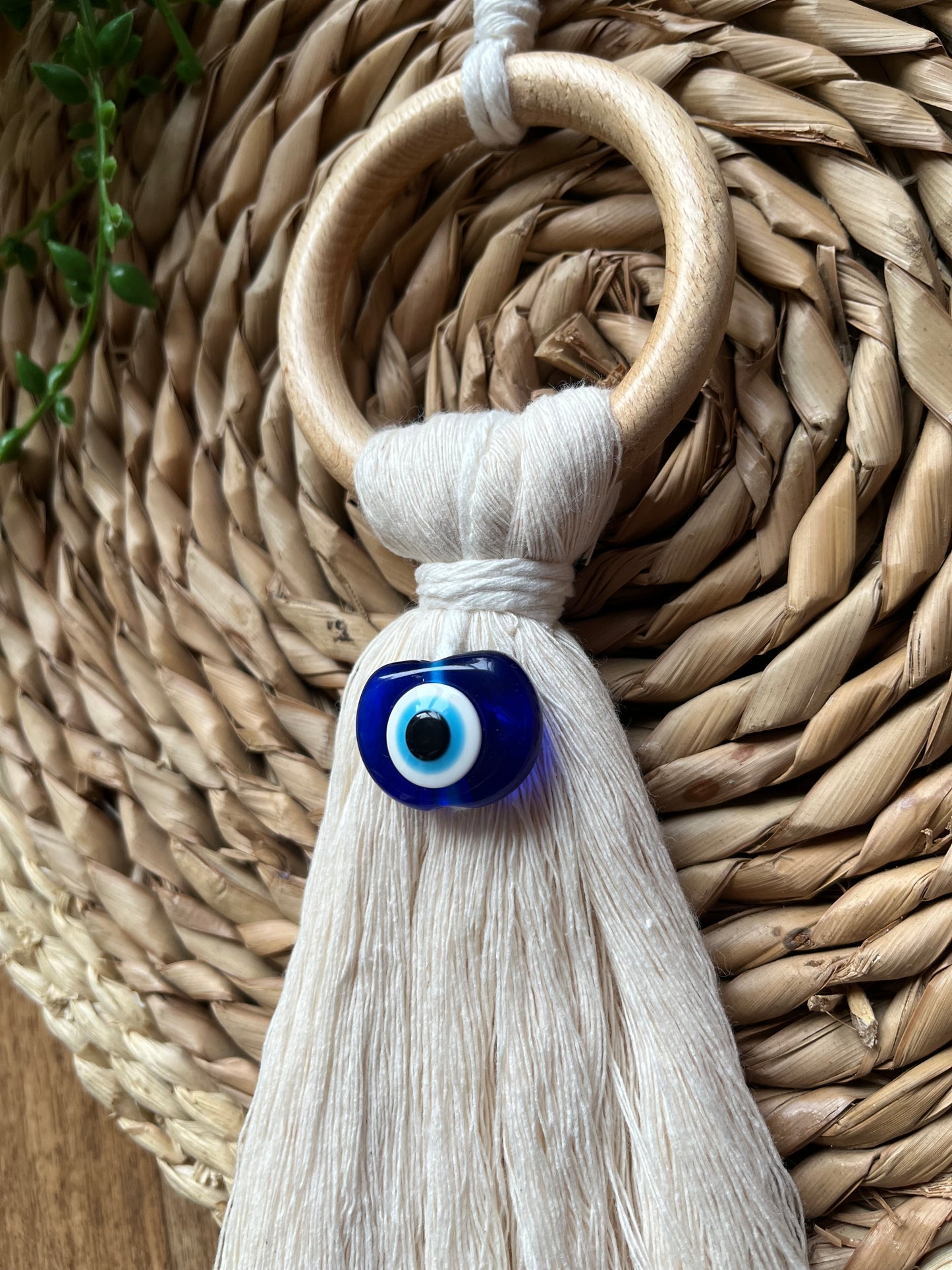 Handmade macrame door hanger, made with recycled cotton, on a wooden ring, with a blue resin evil eye bead.