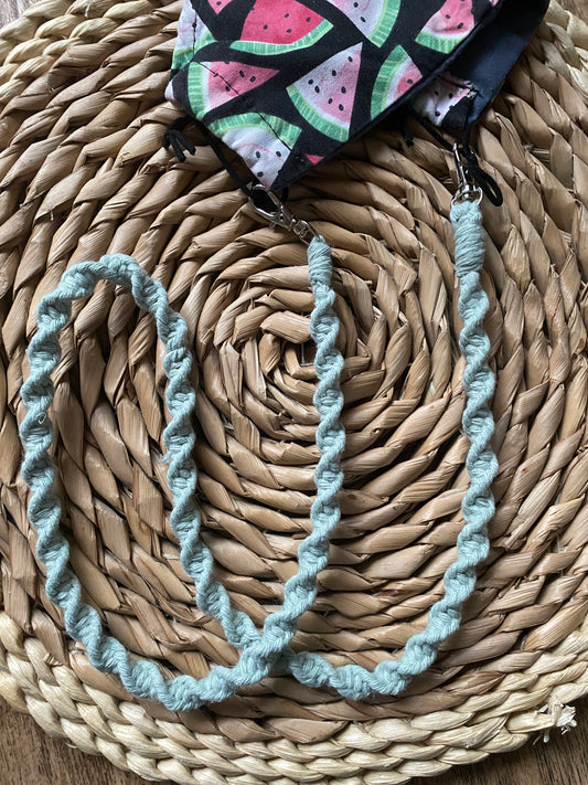 Handmade macramé face mask lanyard in pastel green cotton cord attached by small metal clips on to a face mask which has a watermelon print.