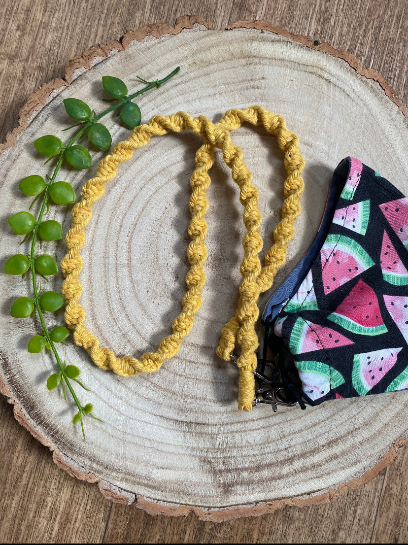 Handmade macramé face mask lanyard in mustard yellow cotton cord attached by small metal clips on to a face mask which has a watermelon print.