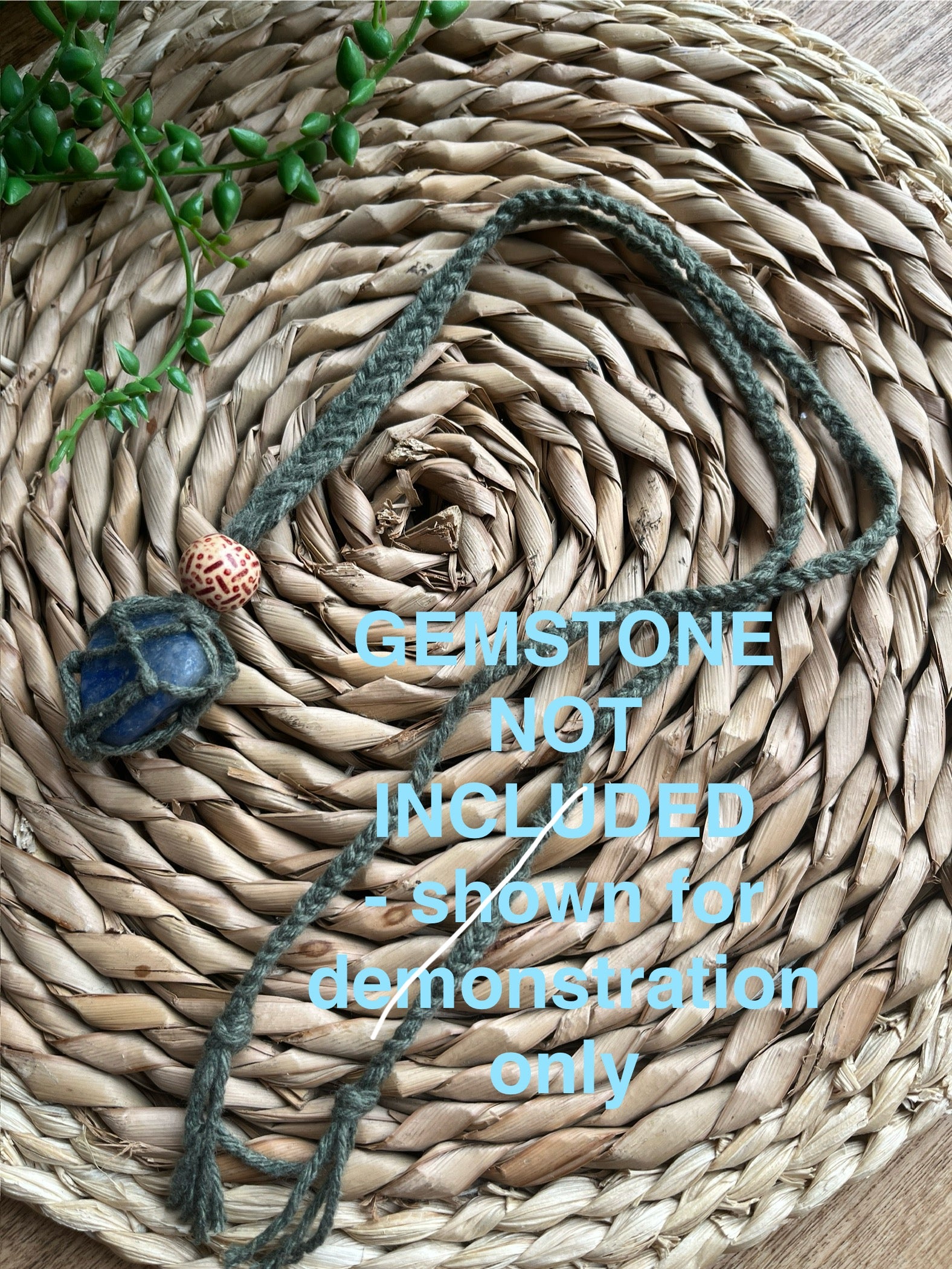 Macrame Gemstone Holder pouch with blue gemstone inside made with eco friendly recycled cotton and a Wooden bead. Blue text on the screen explaining the gemstone is not included.