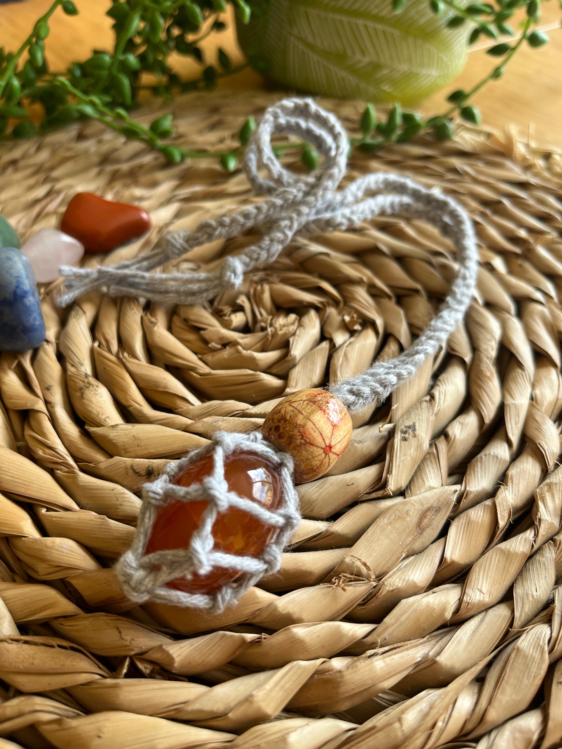 Macrame Gemstone Holder net pouch with orange gemstone inside, made with grey eco friendly recycled cotton and a Wooden bead.