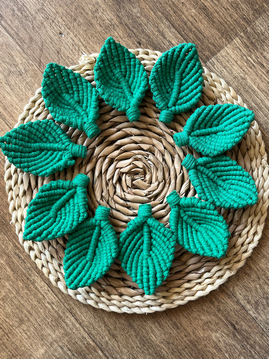 10 green macrame leaf embellishments on a round woven mat.