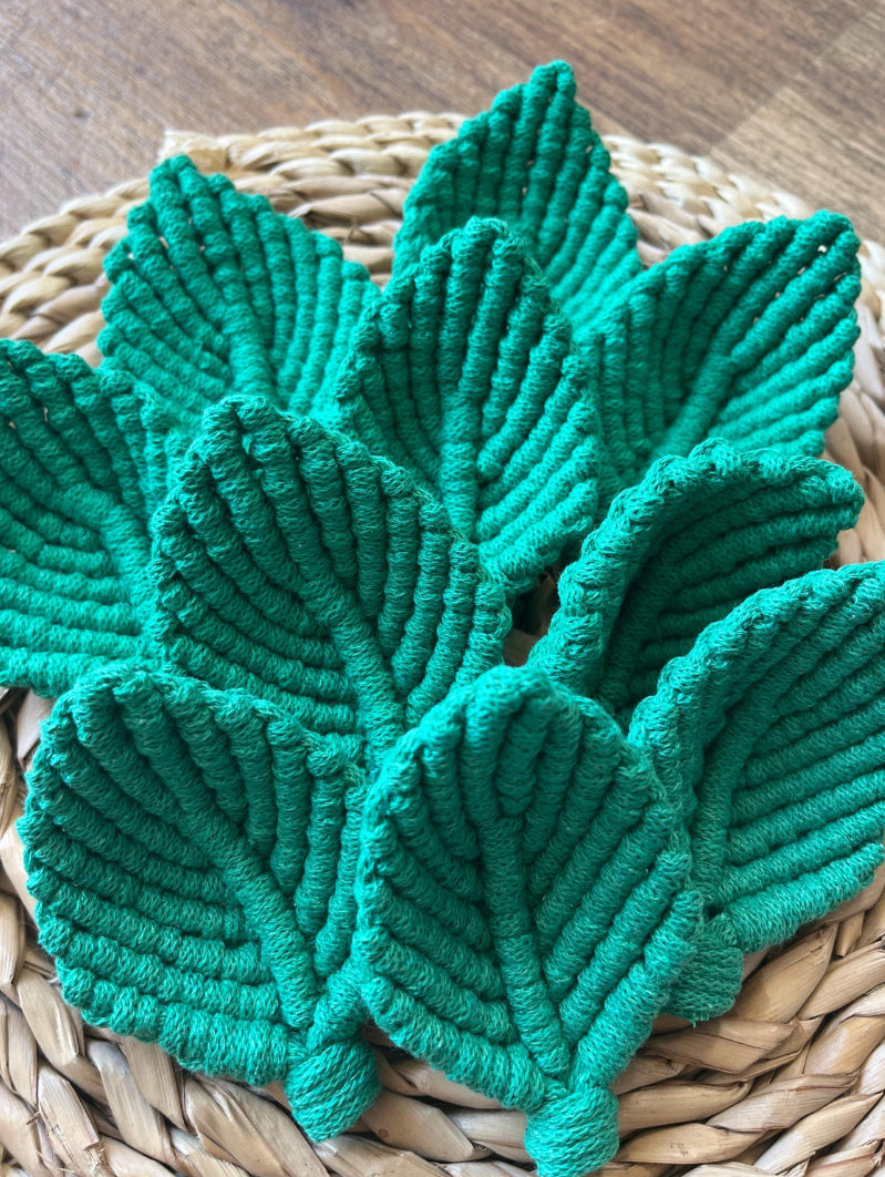 Set of green leaf-shaped embellishments on a woven mat