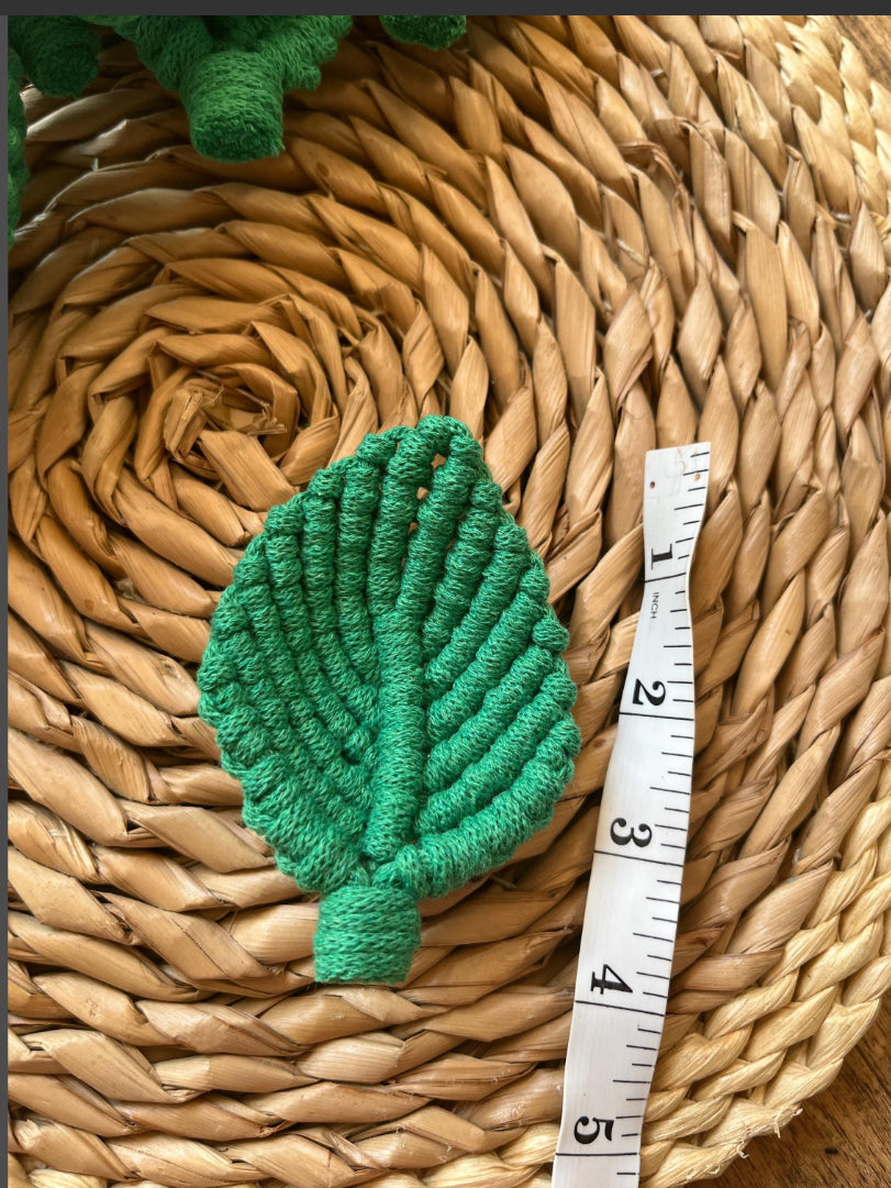 Green leaf-shaped embellishment on a woven mat with a ruler for scale.