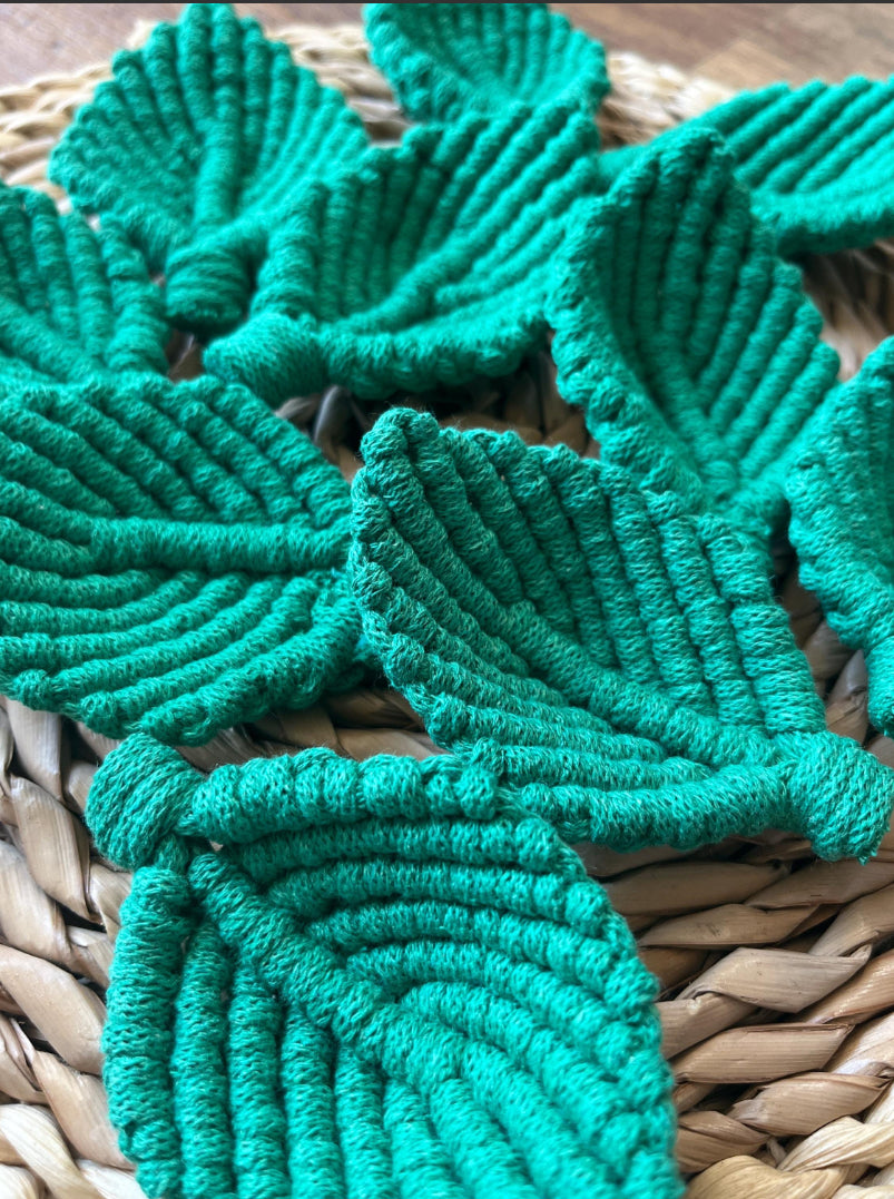 Green textured macrame leaves on a woven surface