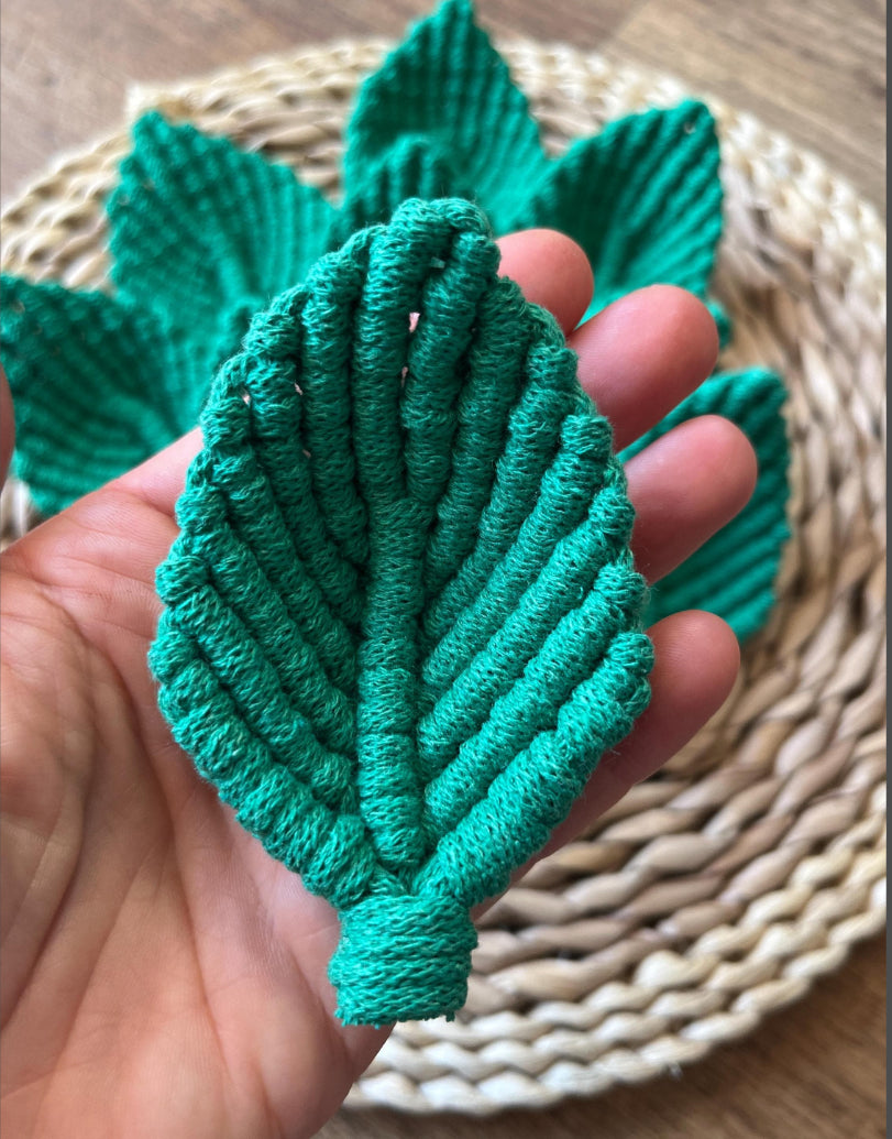 Green textured leaf-shaped embellishments held in a hand with a woven mat background