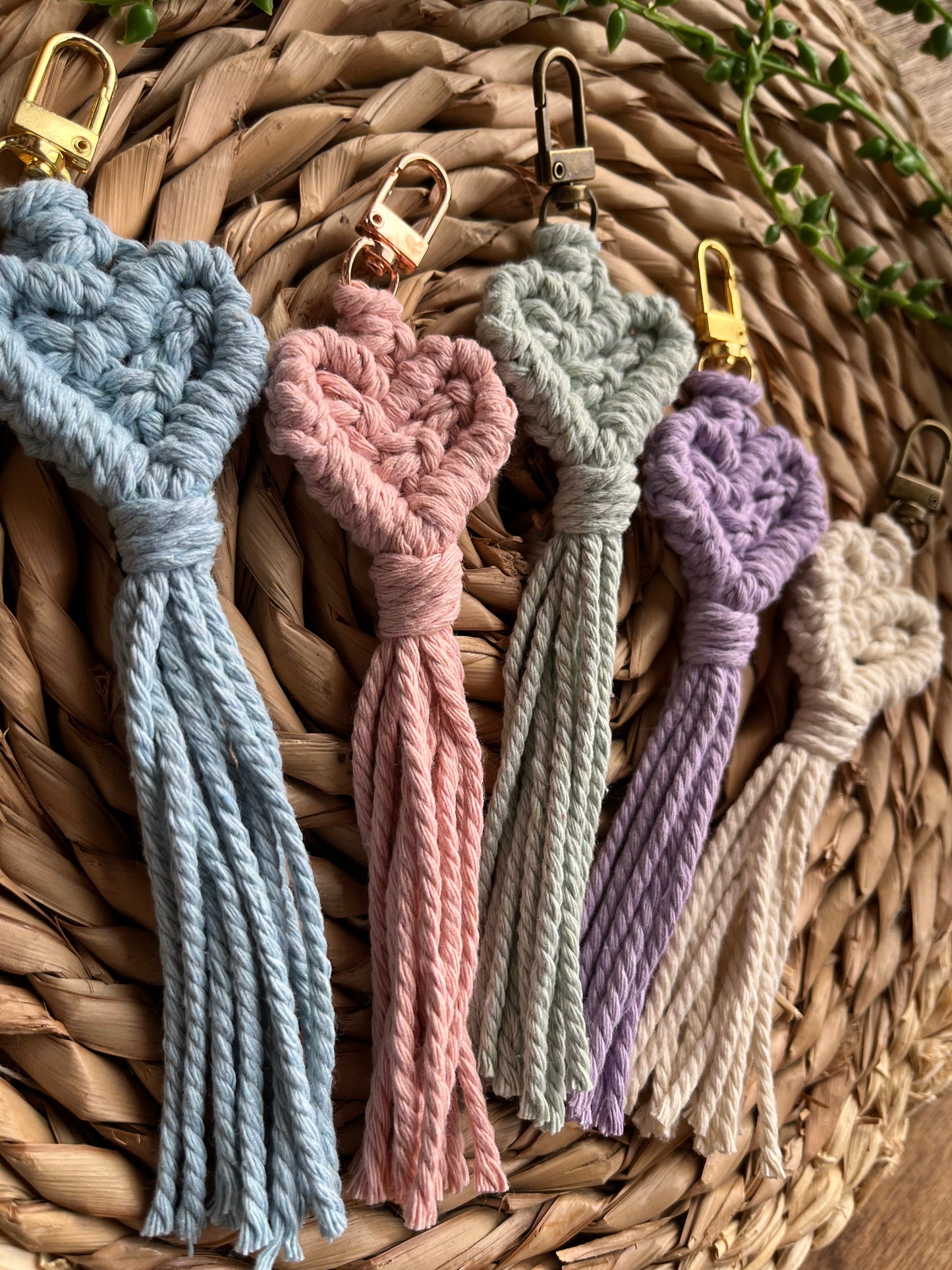 A side close up image of 5 handmade macrame heart shaped keychains, made with recycled cotton in a choice of pastel colours.