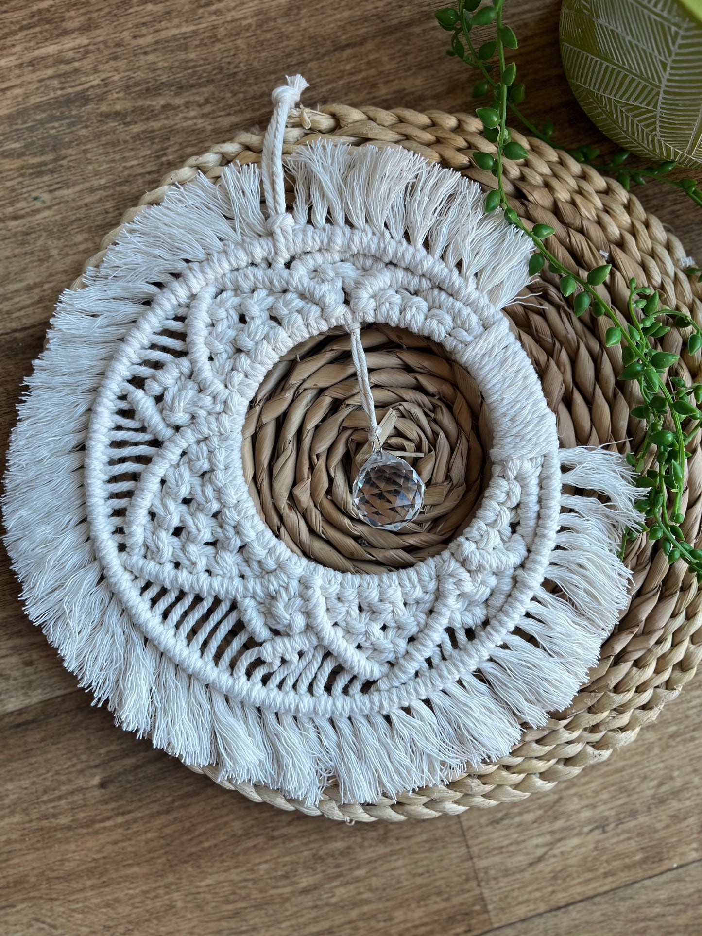 Handmade macrame moon shaped boho sun catcher made with recycled cotton natural yarn and a crystal prism in the centre.