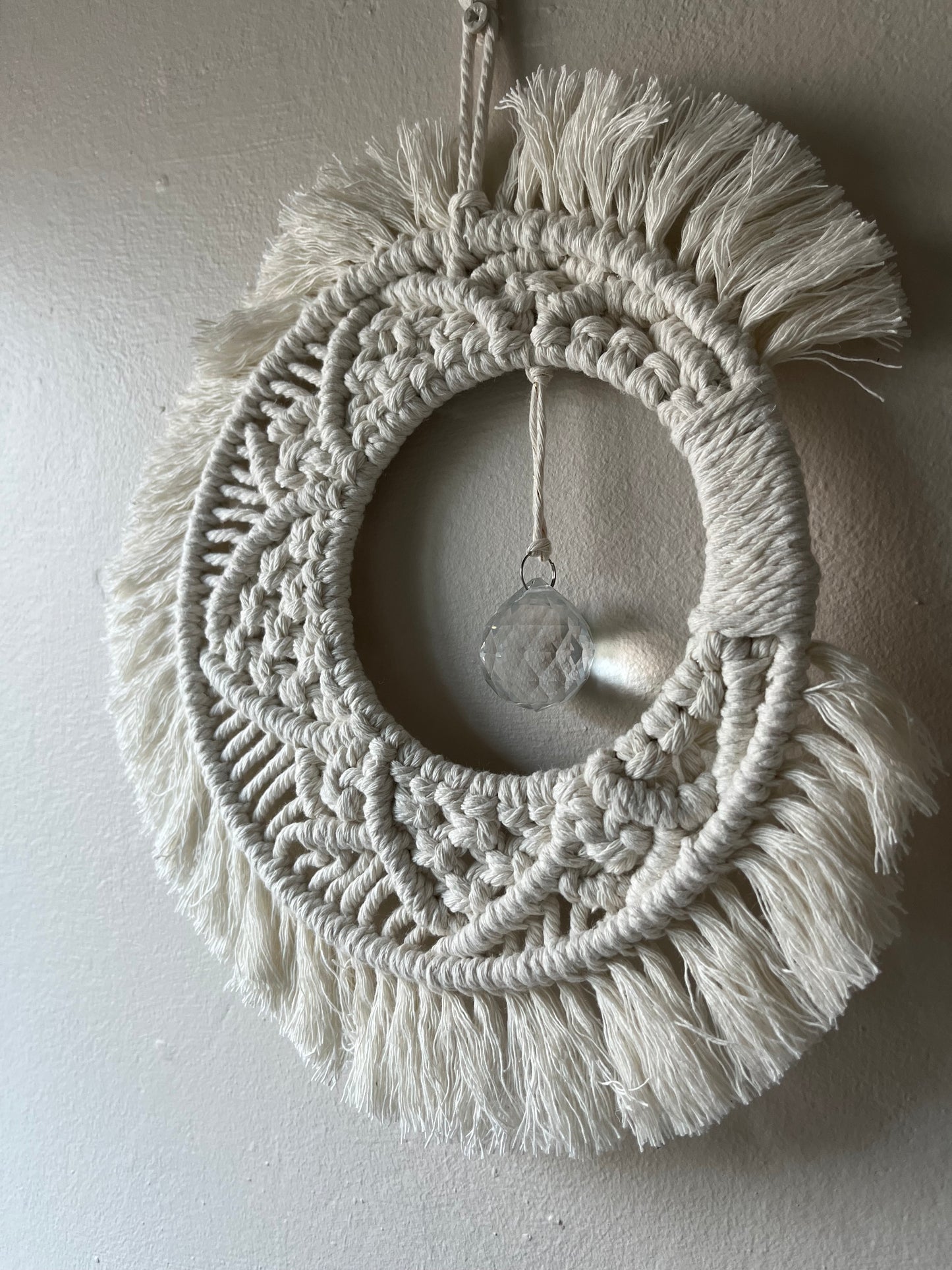 Handmade macrame moon shaped boho sun catcher made with recycled cotton natural yarn and a crystal prism in the centre.