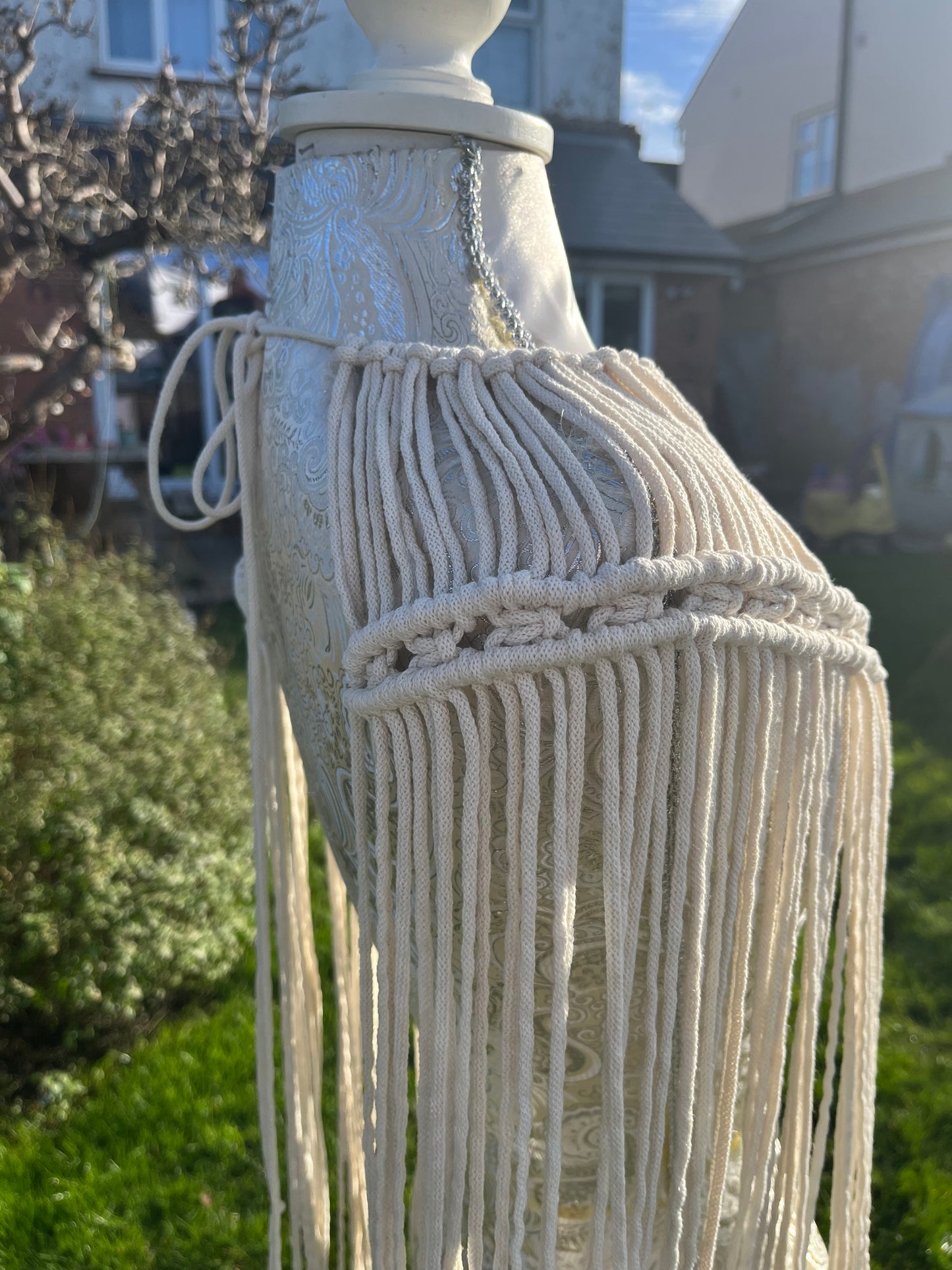 a mannequin outside in the sunshine displays a handmade macrame shoulder accessory epaulette made with natural recycled cotton