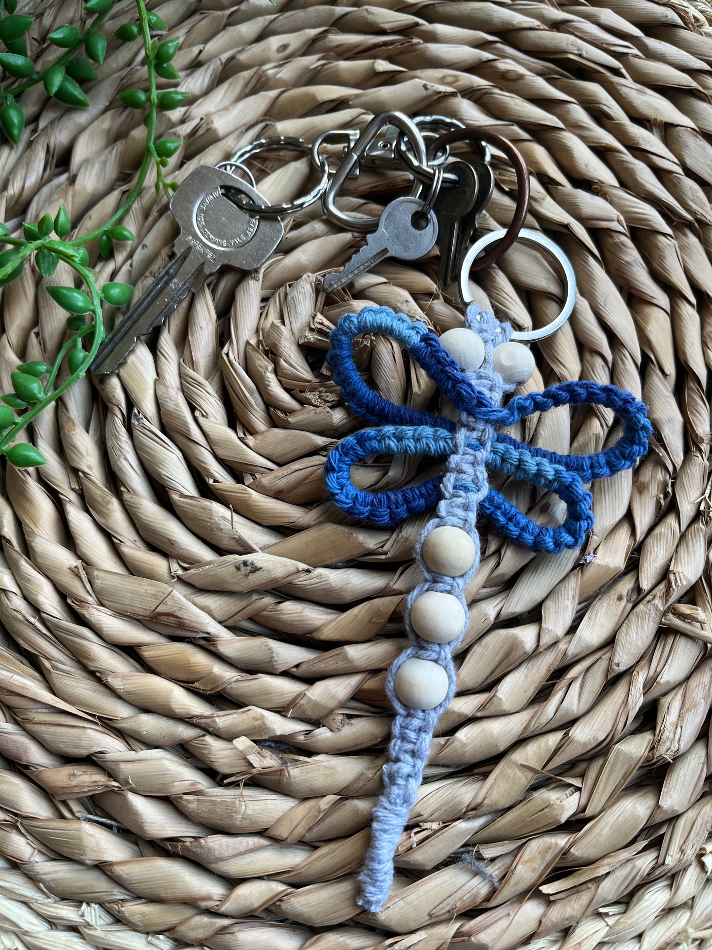 Handmade macrame dragonfly keyring or bag charm, made using shades of blue recycled cotton, on a metal split ring, with small wooden beads, the keyring is attached to a small set of silver keys.