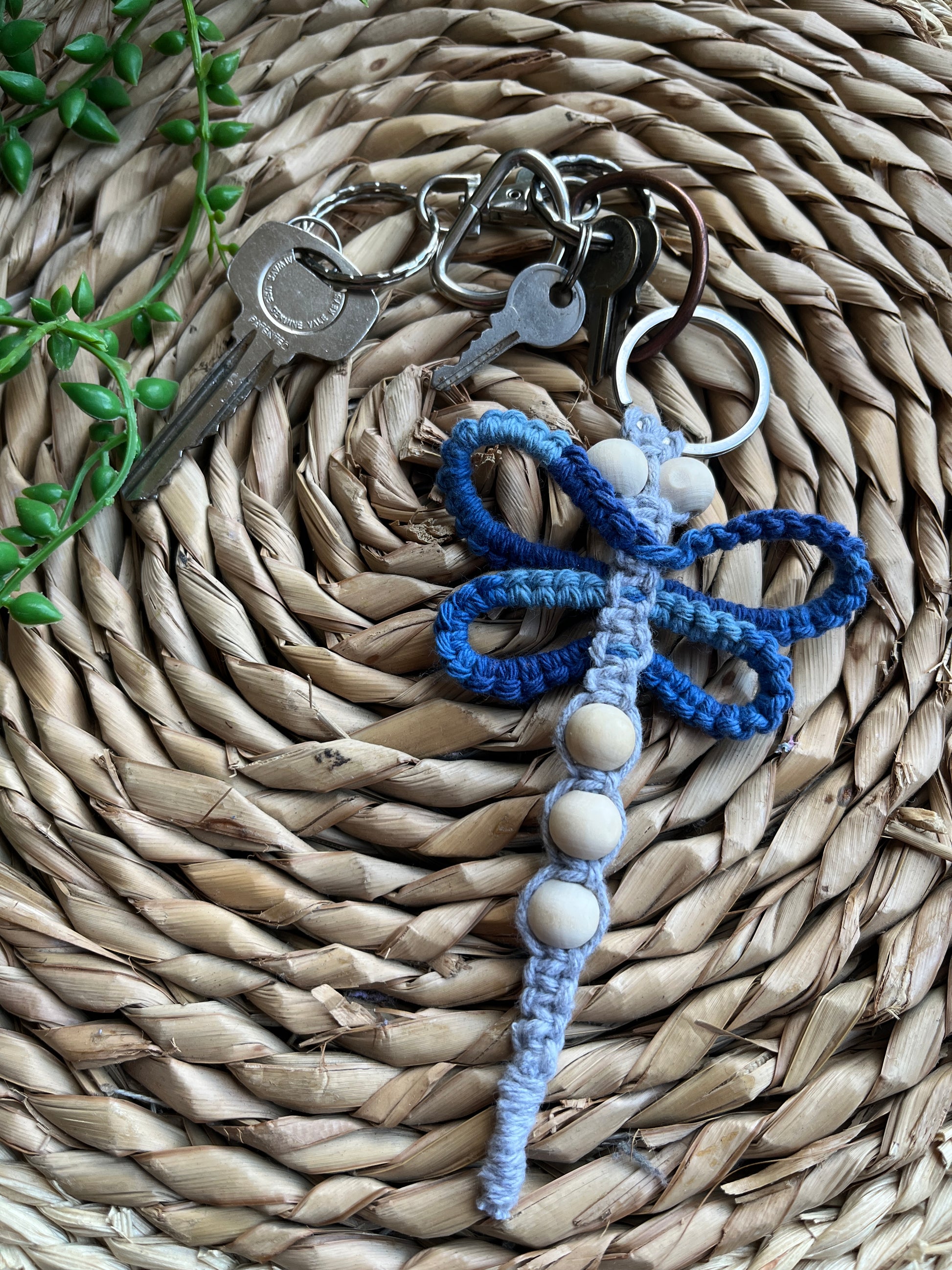 Handmade macrame dragonfly keyring or bag charm, made using shades of blue recycled cotton, on a metal split ring, with small wooden beads, the keyring is attached to a small set of silver keys.