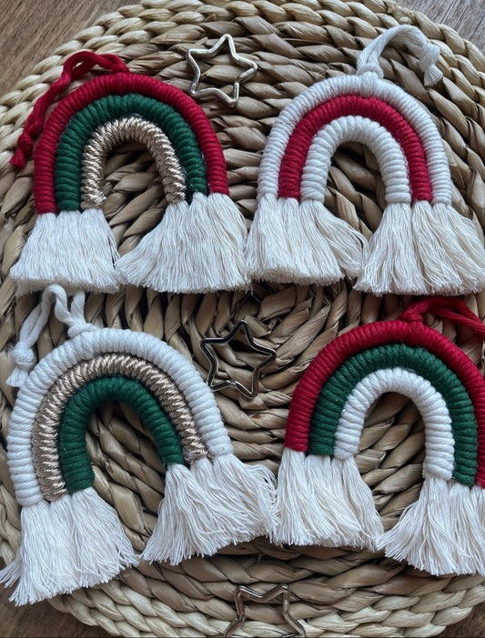 Four handmade macrame rainbows in festive christmas colours, laid next to each other on a round wicker mat.