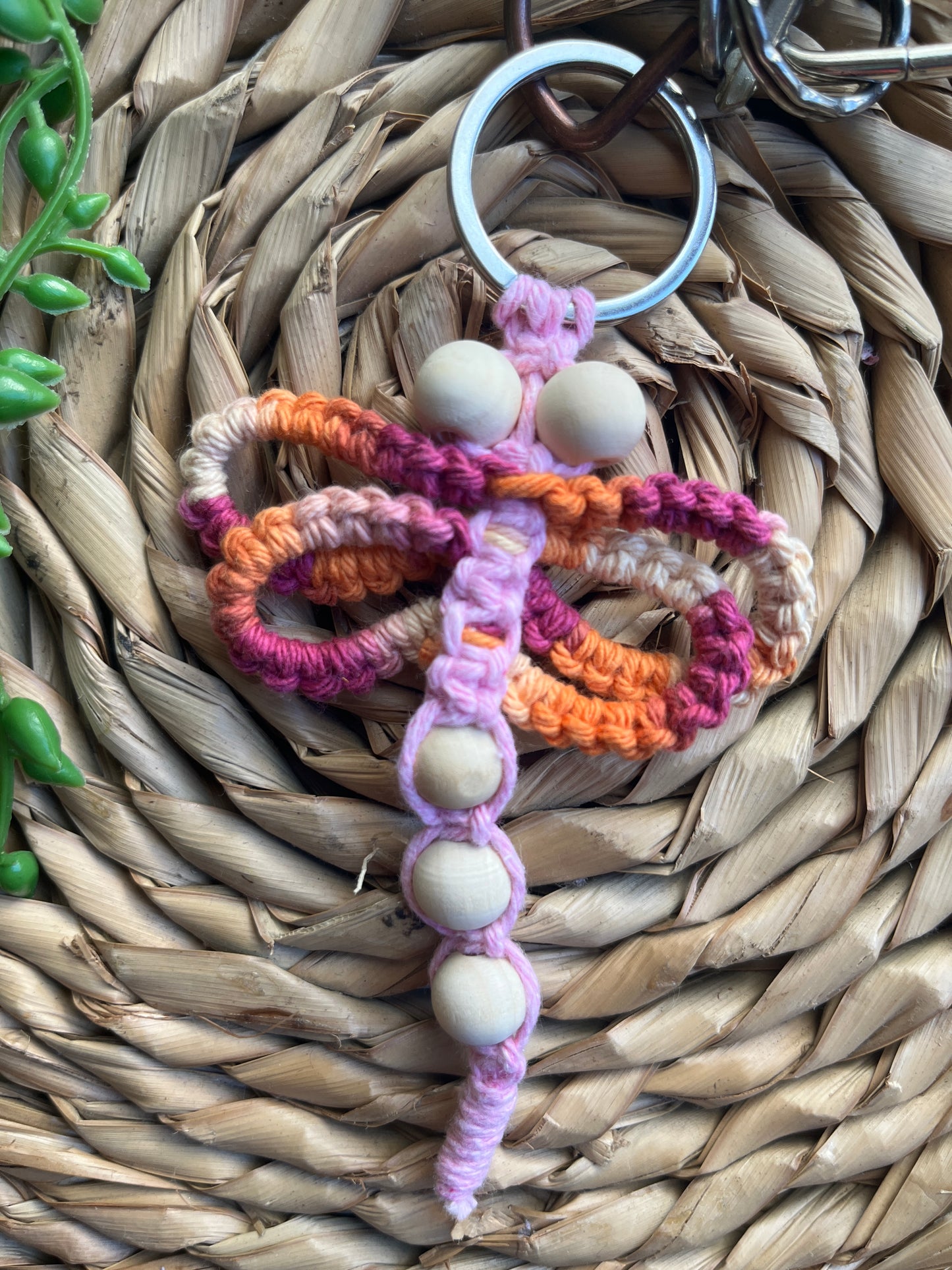 Handmade macrame dragonfly keyring or bag charm, made using shades of pink recycled cotton, on a metal split ring, with small wooden beads.
