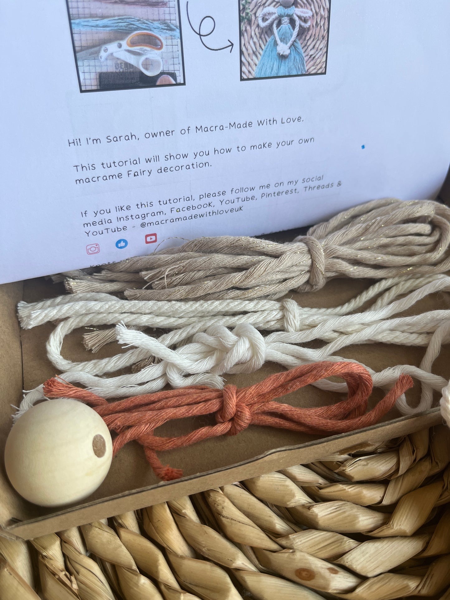 Pre cut yarn and a wooden bead on an open box with printed instructions for a craft kit in the background.