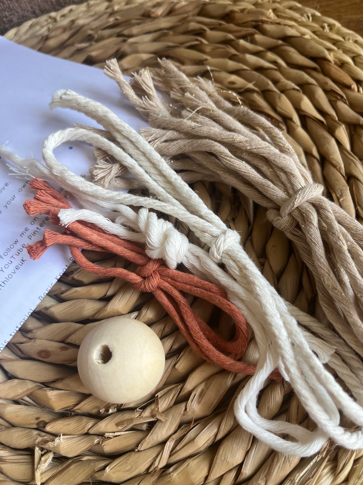 Cotton yarns and a wooden bead laid neatly on a woven mat.