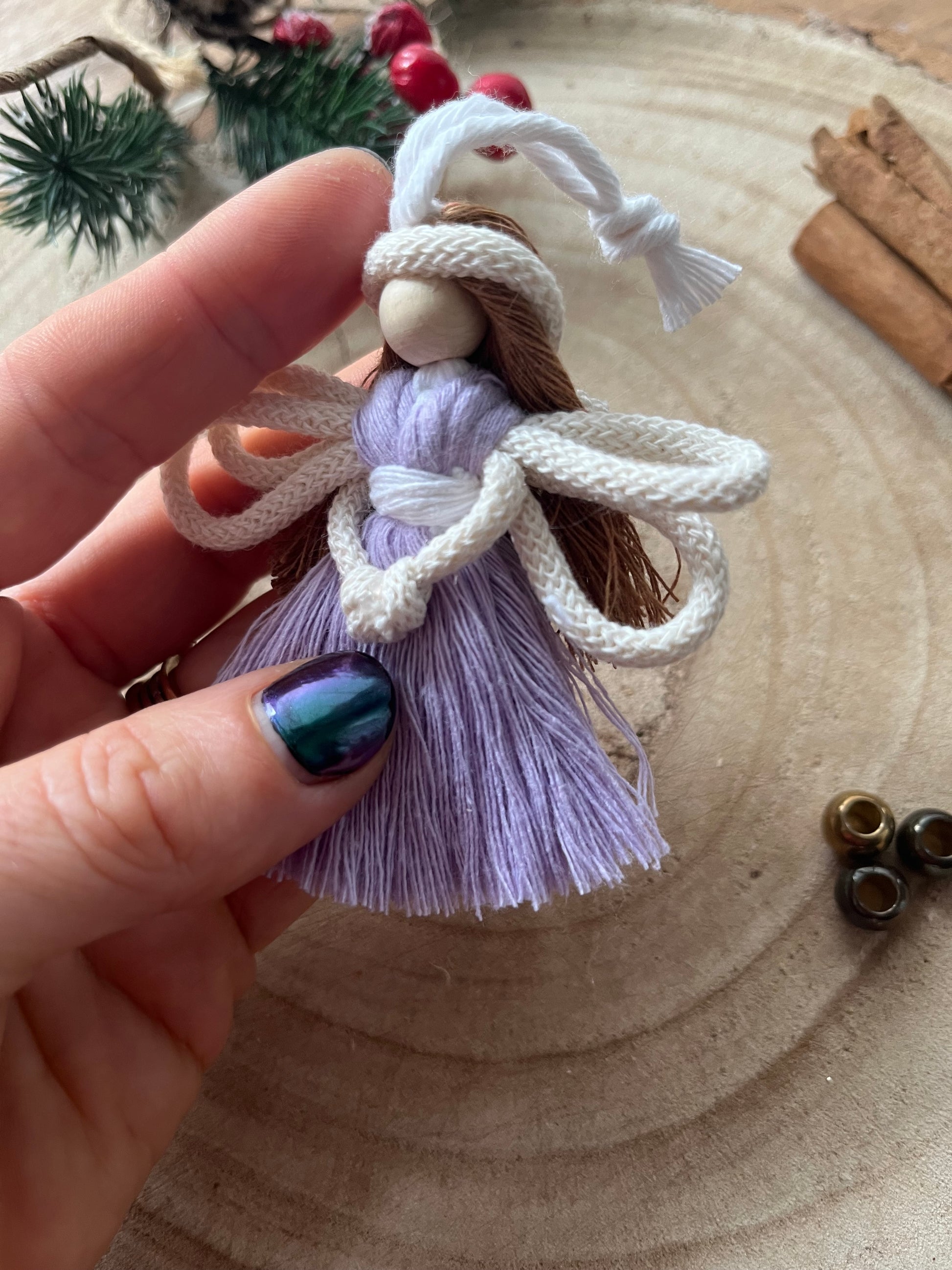Detailed view of handcrafted macrame fairy with knotted wings and lilac cotton dress.