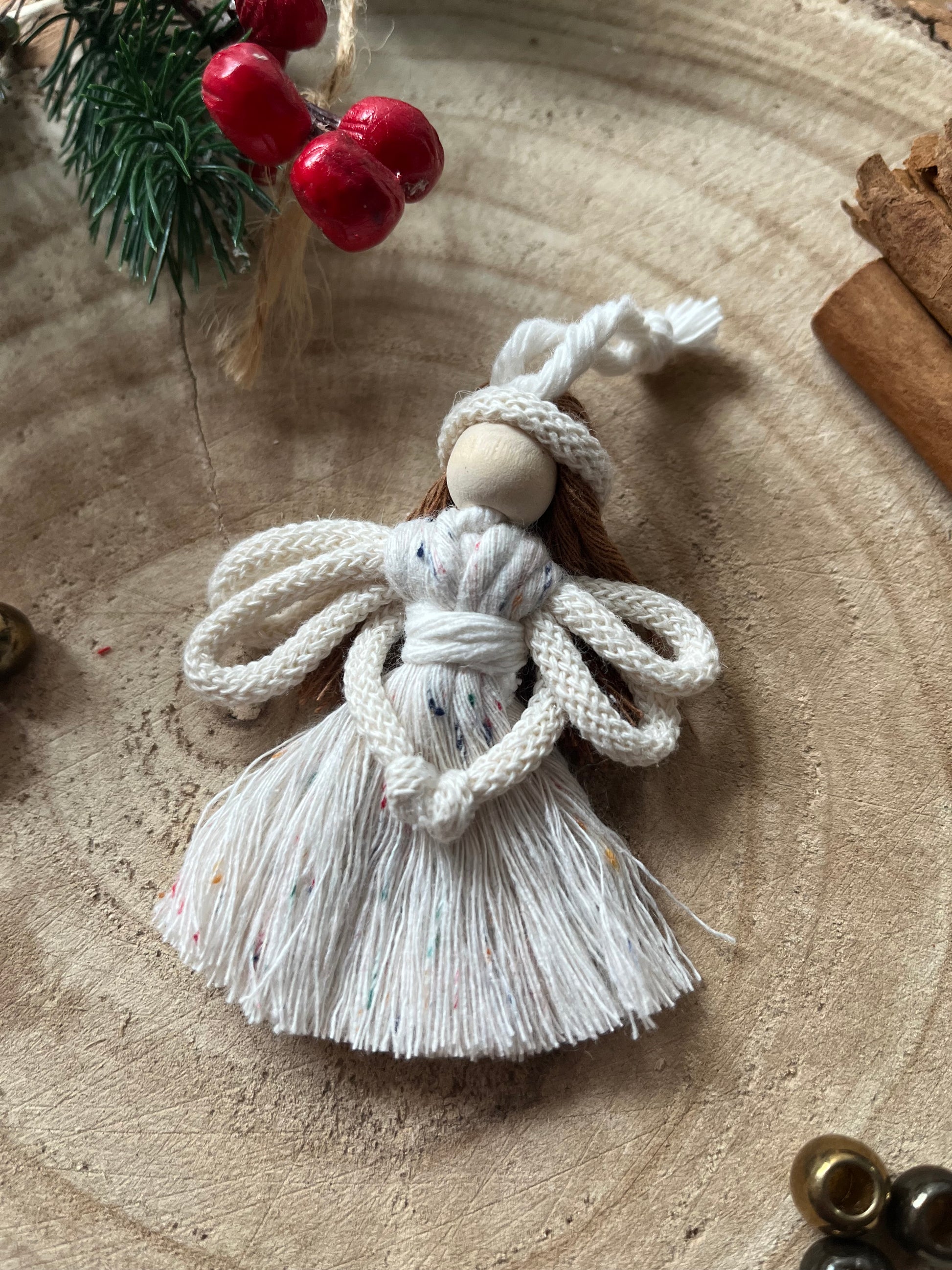 8cm handmade macrame fairy Christmas tree decoration in natural cotton, on a wooden surface.