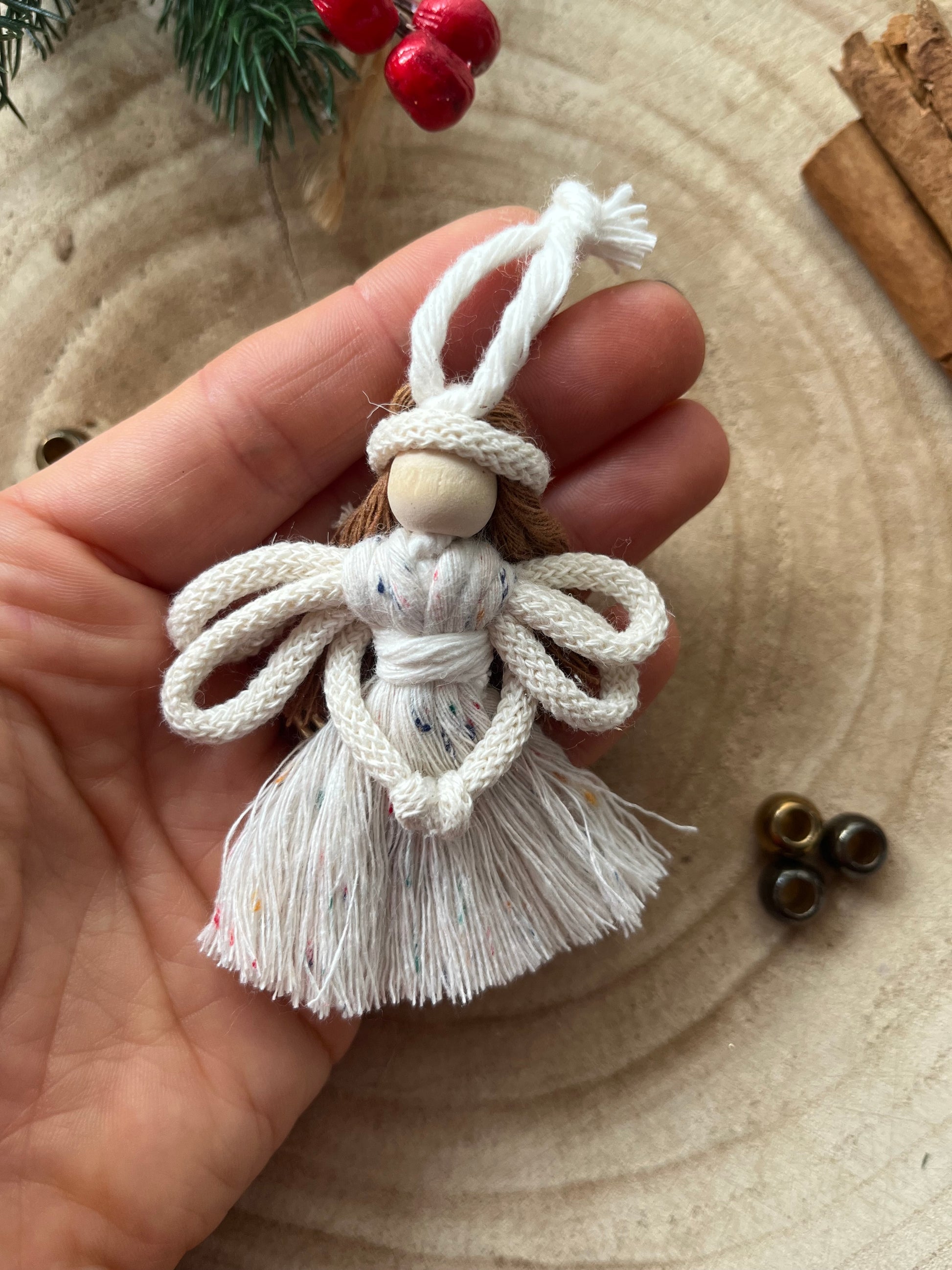 Close up of a hand holding a handcrafted macrame fairy with knotted wings and dress.
