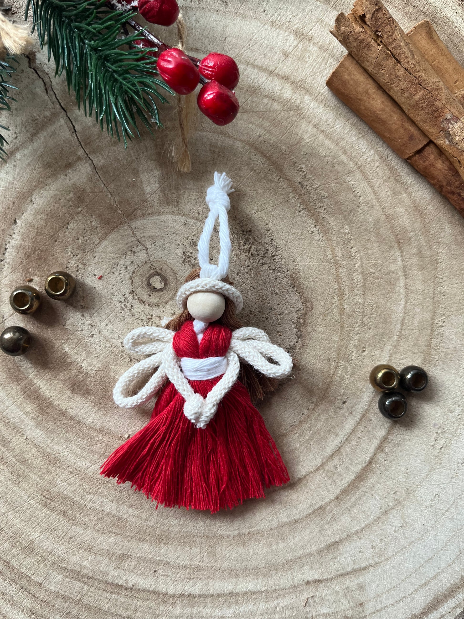 8cm handmade macrame fairy Christmas tree decoration in red cotton, on a wooden surface.