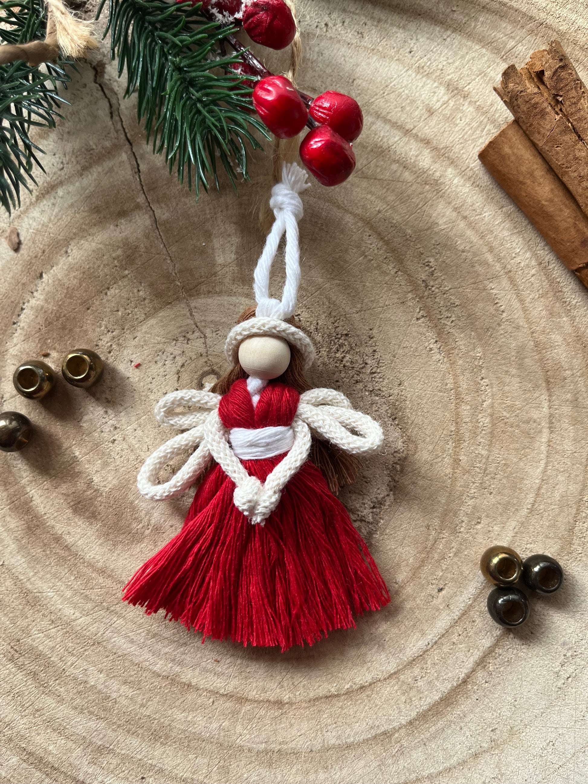 8cm handmade macrame fairy Christmas tree decoration in red cotton, on a wooden surface.