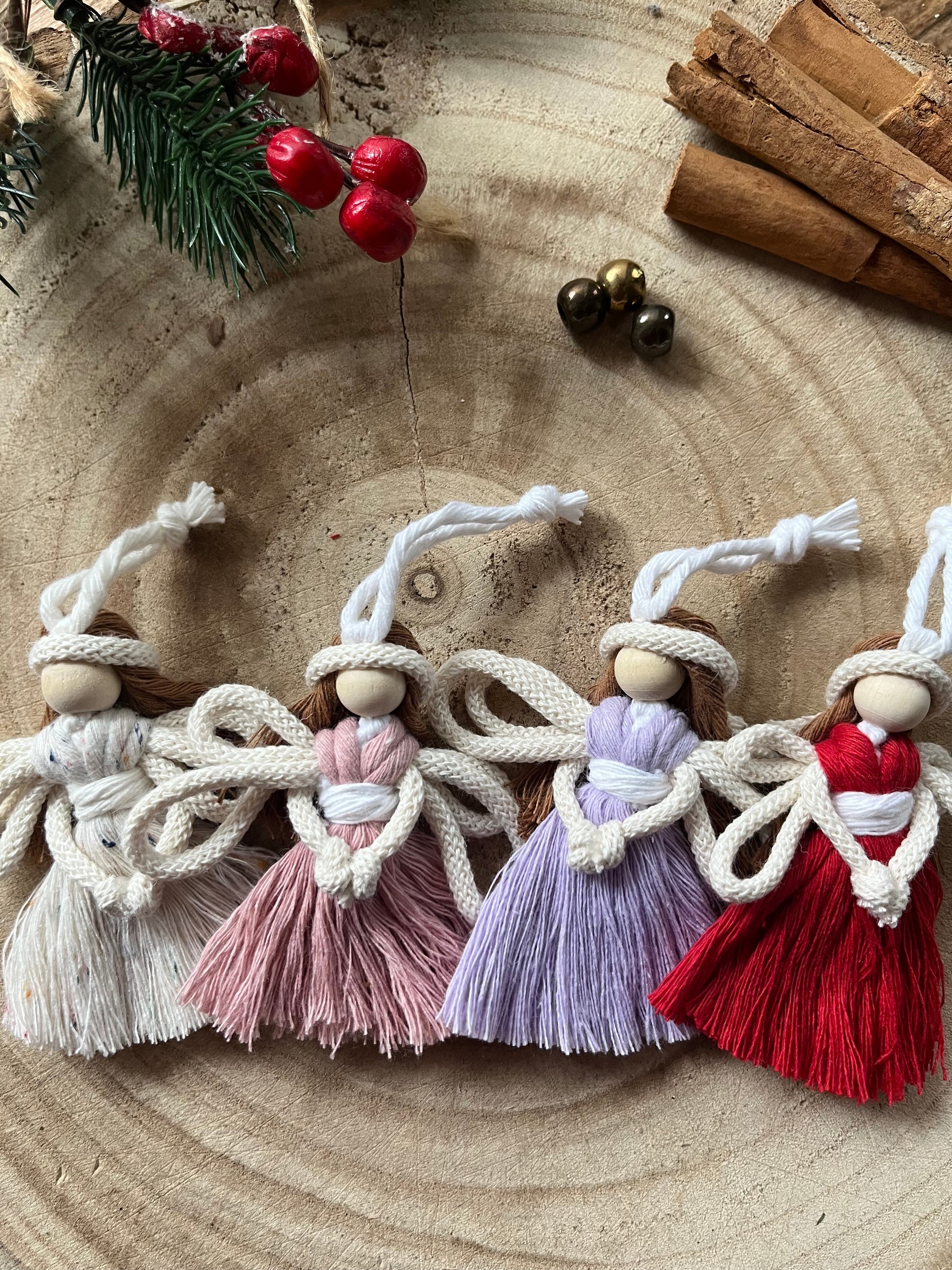 Four 8cm handmade macrame fairy Christmas tree decorations, on a wooden surface.
