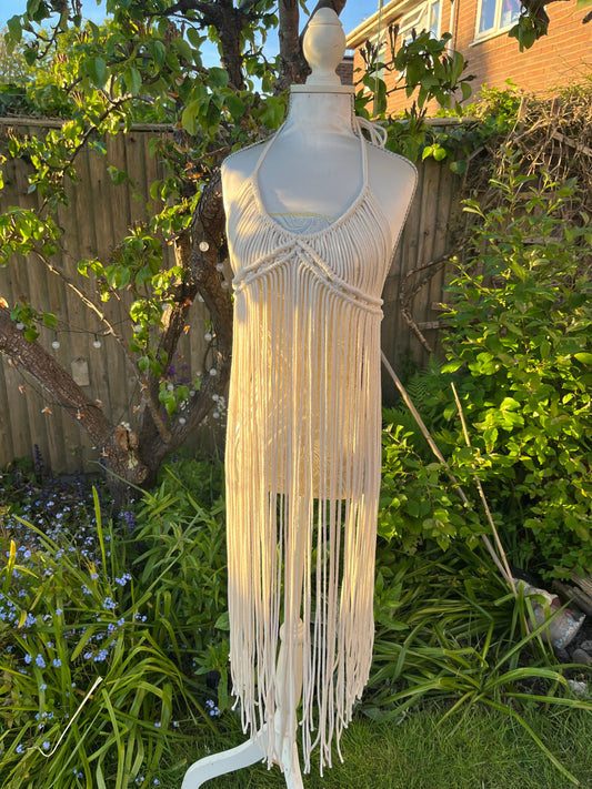 A beige, one-size boho goddess dress with tie finishes at the neck and waist, displayed on a mannequin outdoors.