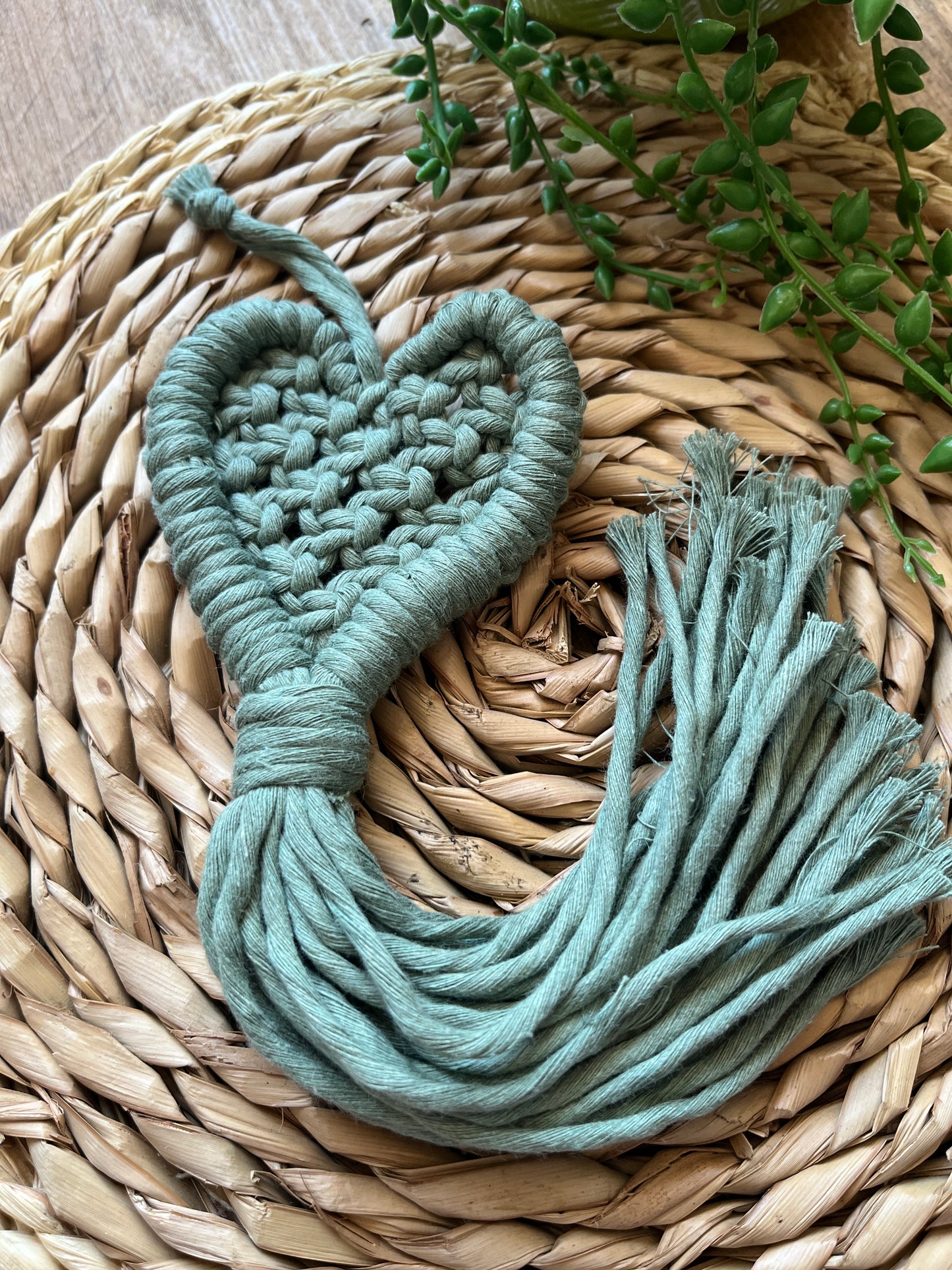 Close up of a macrame heart shaped decoration on a woven mat