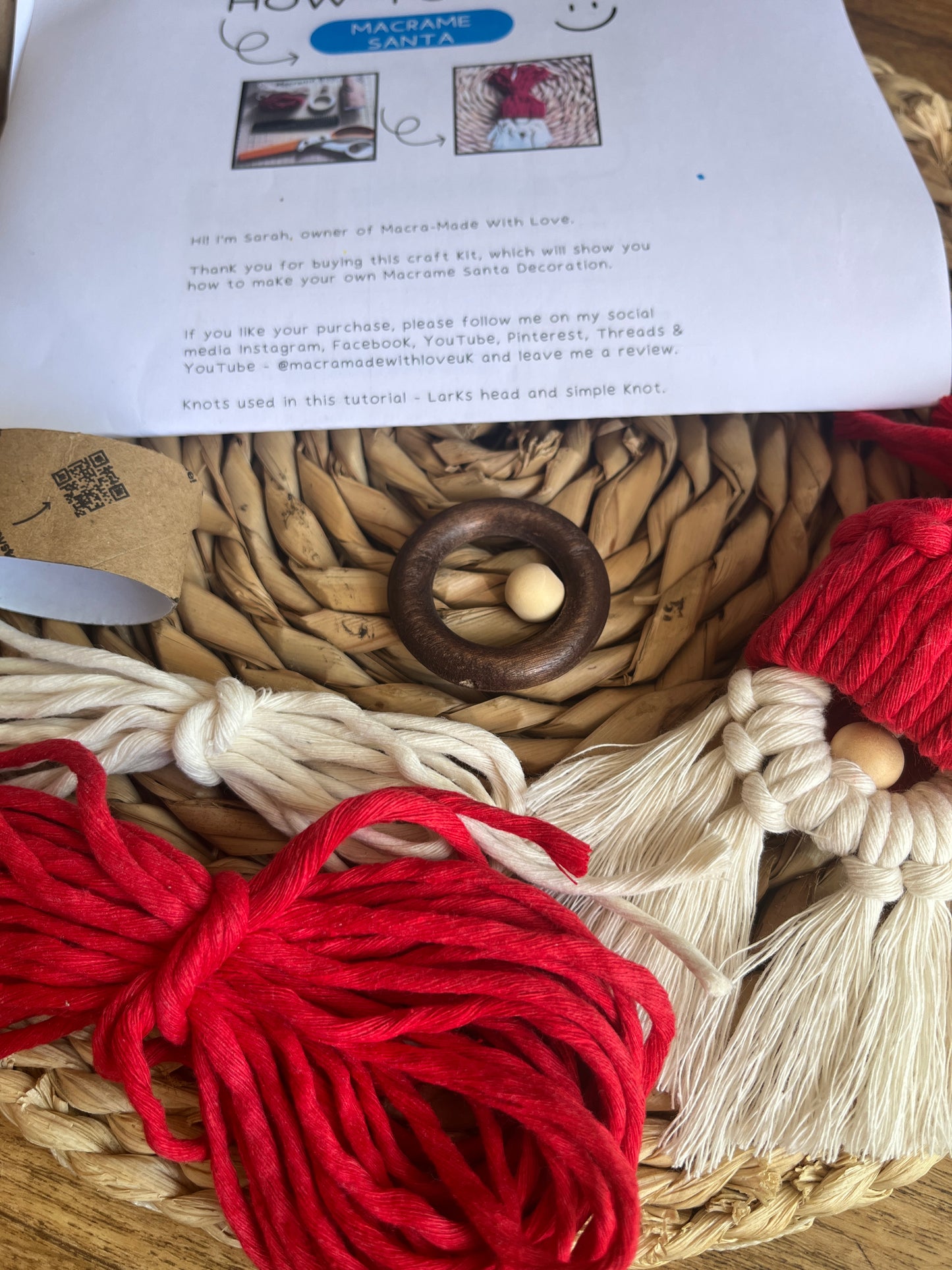 Gnome craft project with yarn, wooden ring, and instructions on a woven mat.