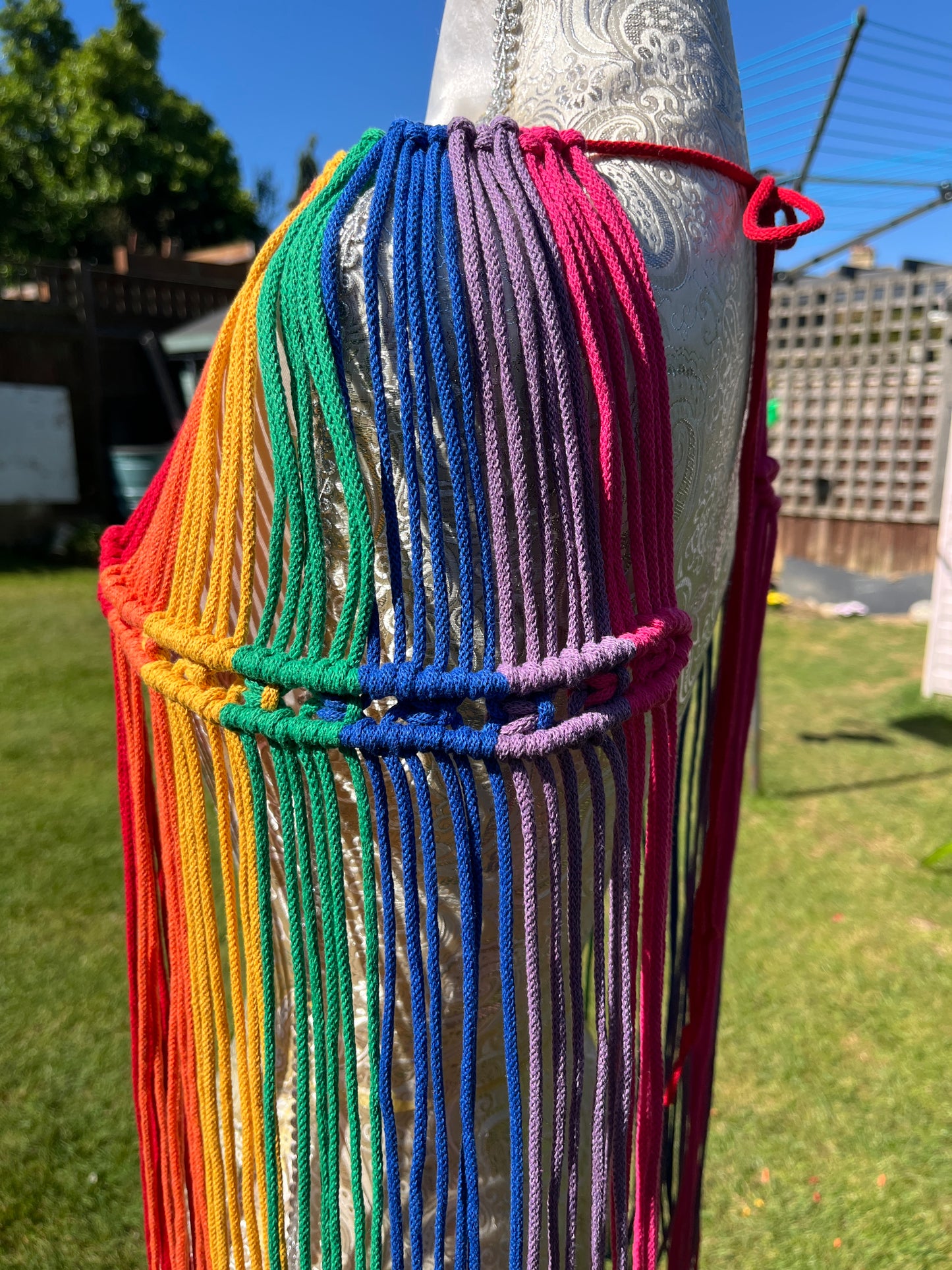 A mannequin stands outside in the sunshine with a handmade macrame shoulder accessory epaulette on it.