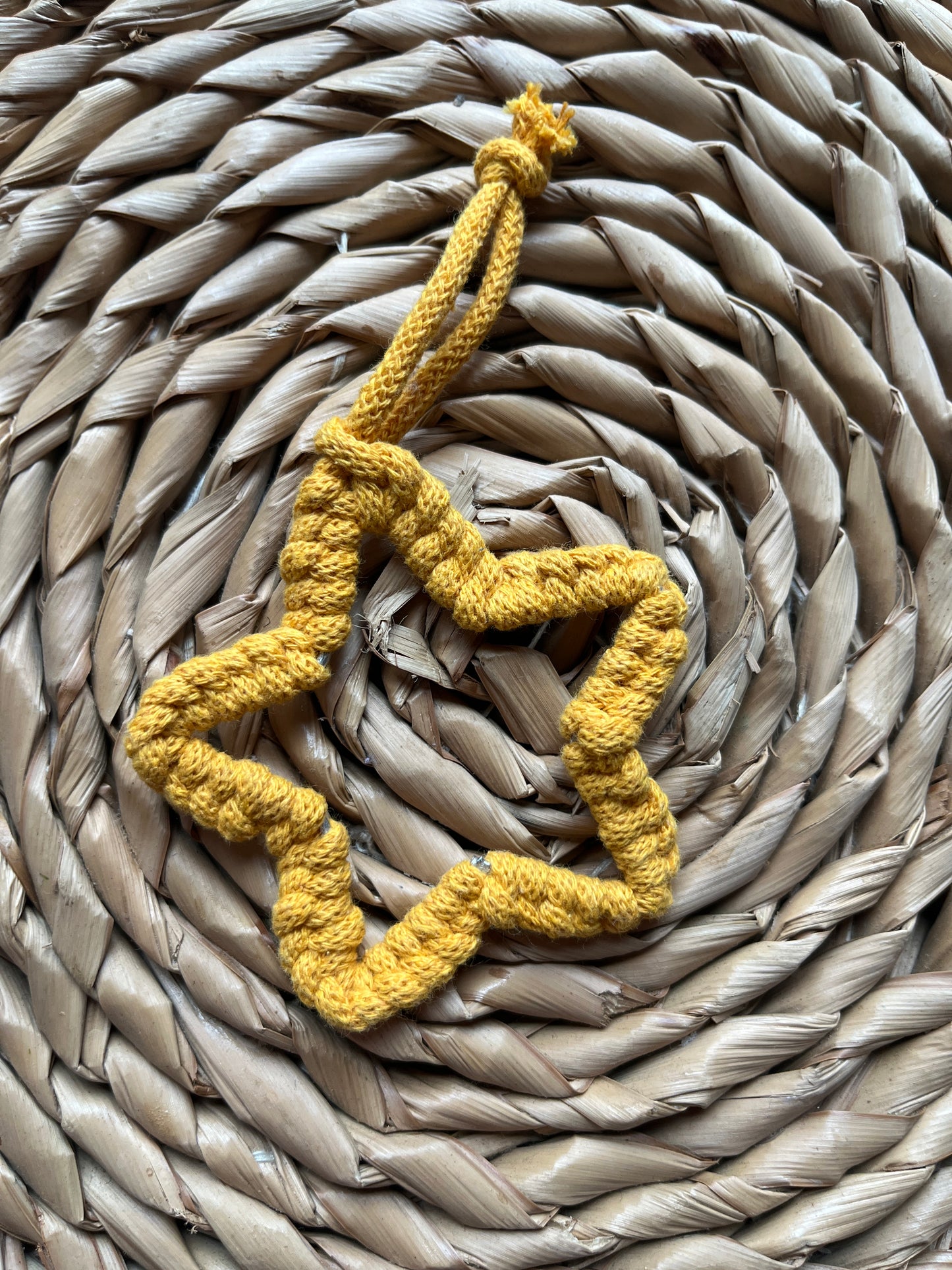 Yellow macrame heart decoration on a woven mat