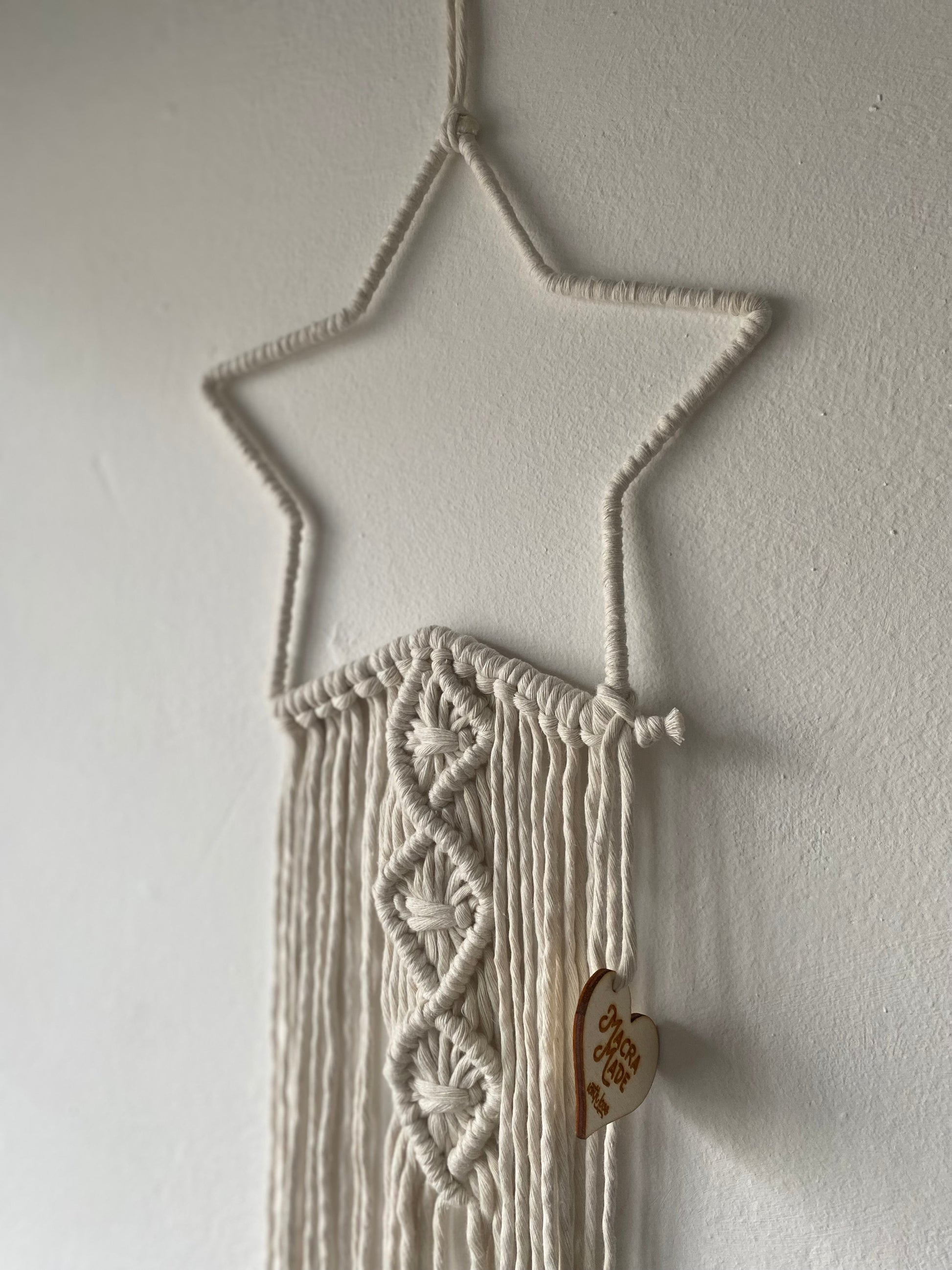 Close up of a macrame star shape wall hanging with long hanging tails.