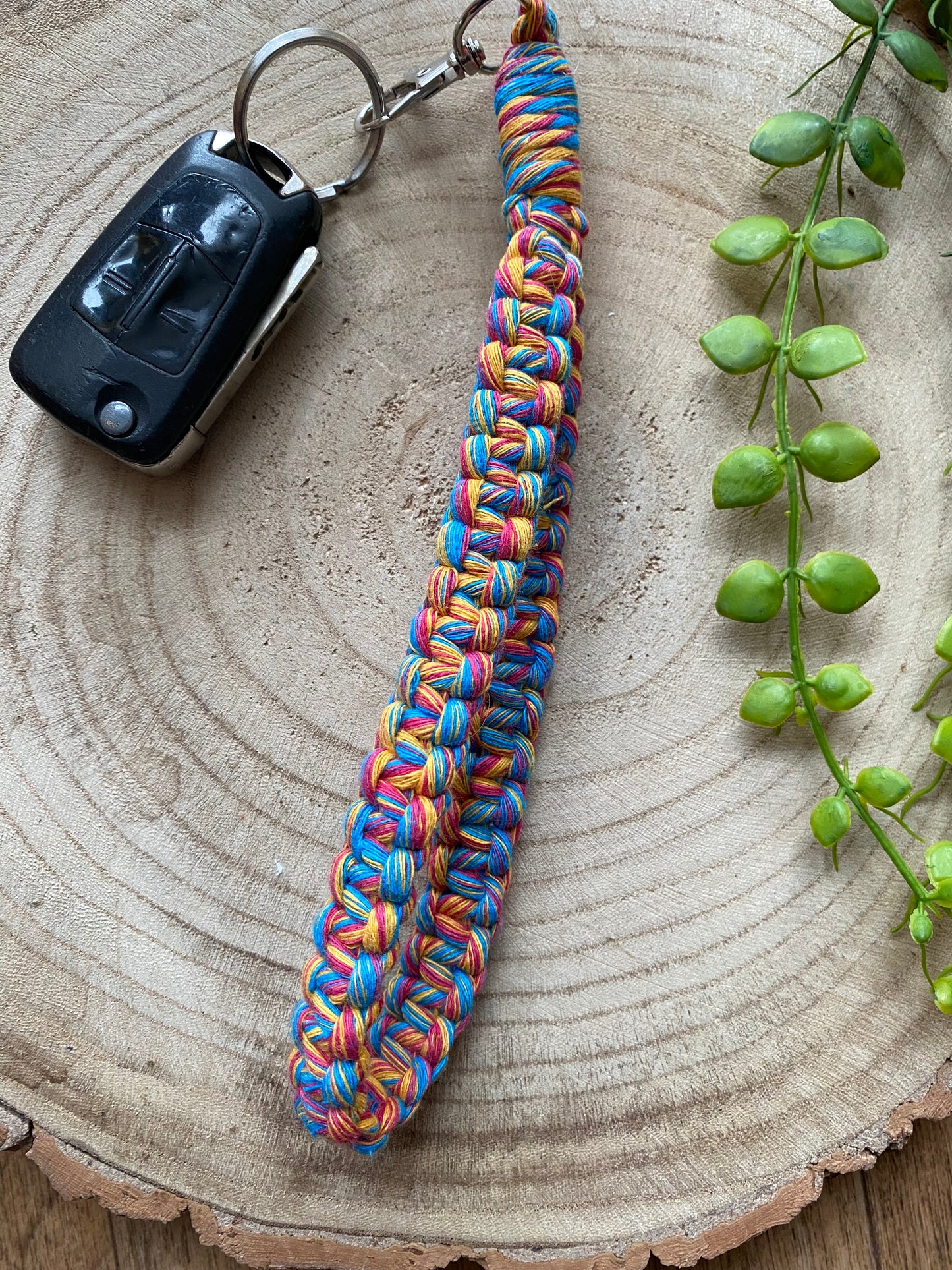 Handmade macrame wristlet keychain with metal clasp, made with multicoloured recycled cotton. Shown attached to a single car key.