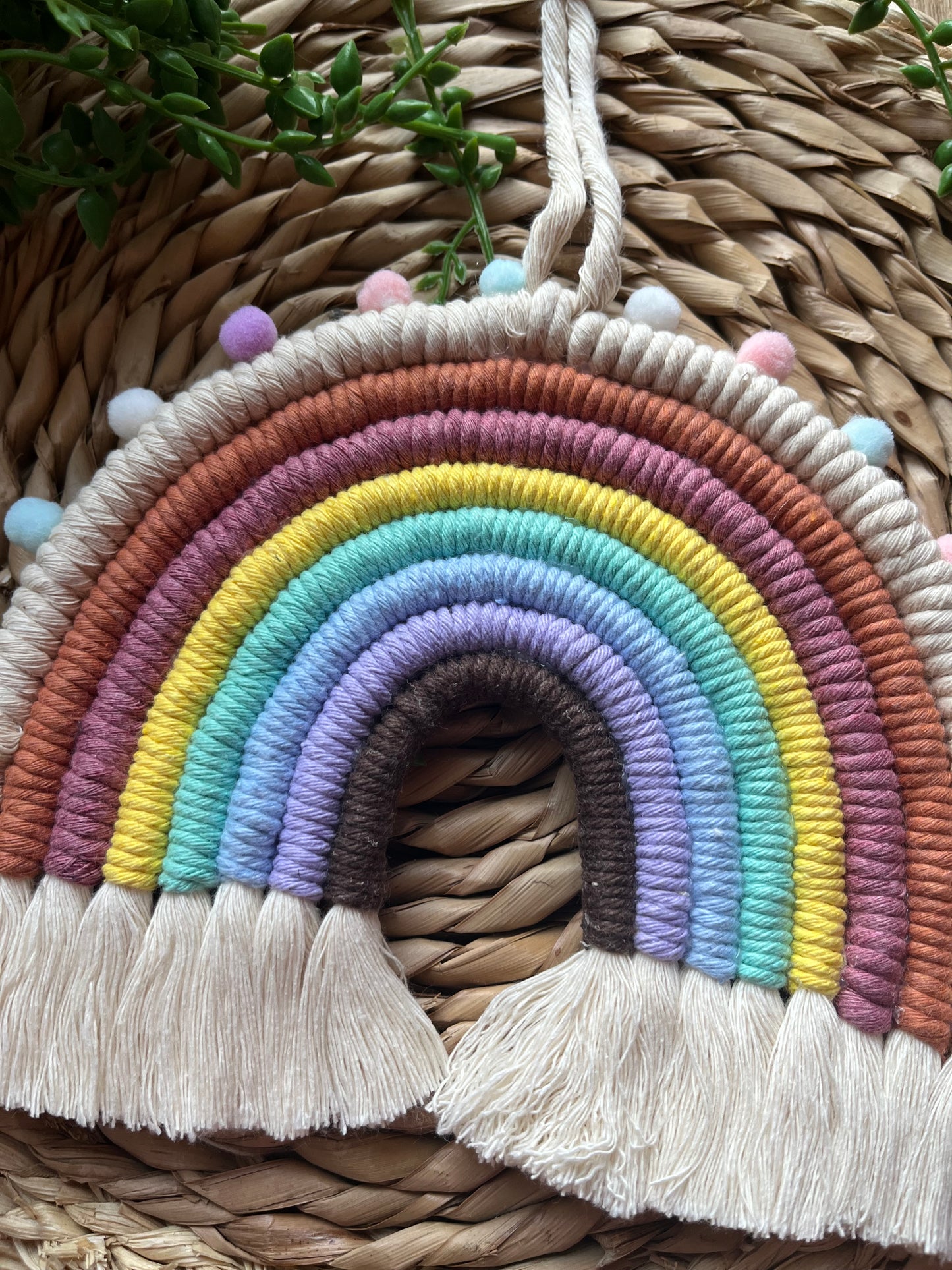 Handmade macrame rainbow, made with pastel shades of recycled cotton and finished with small pom poms.