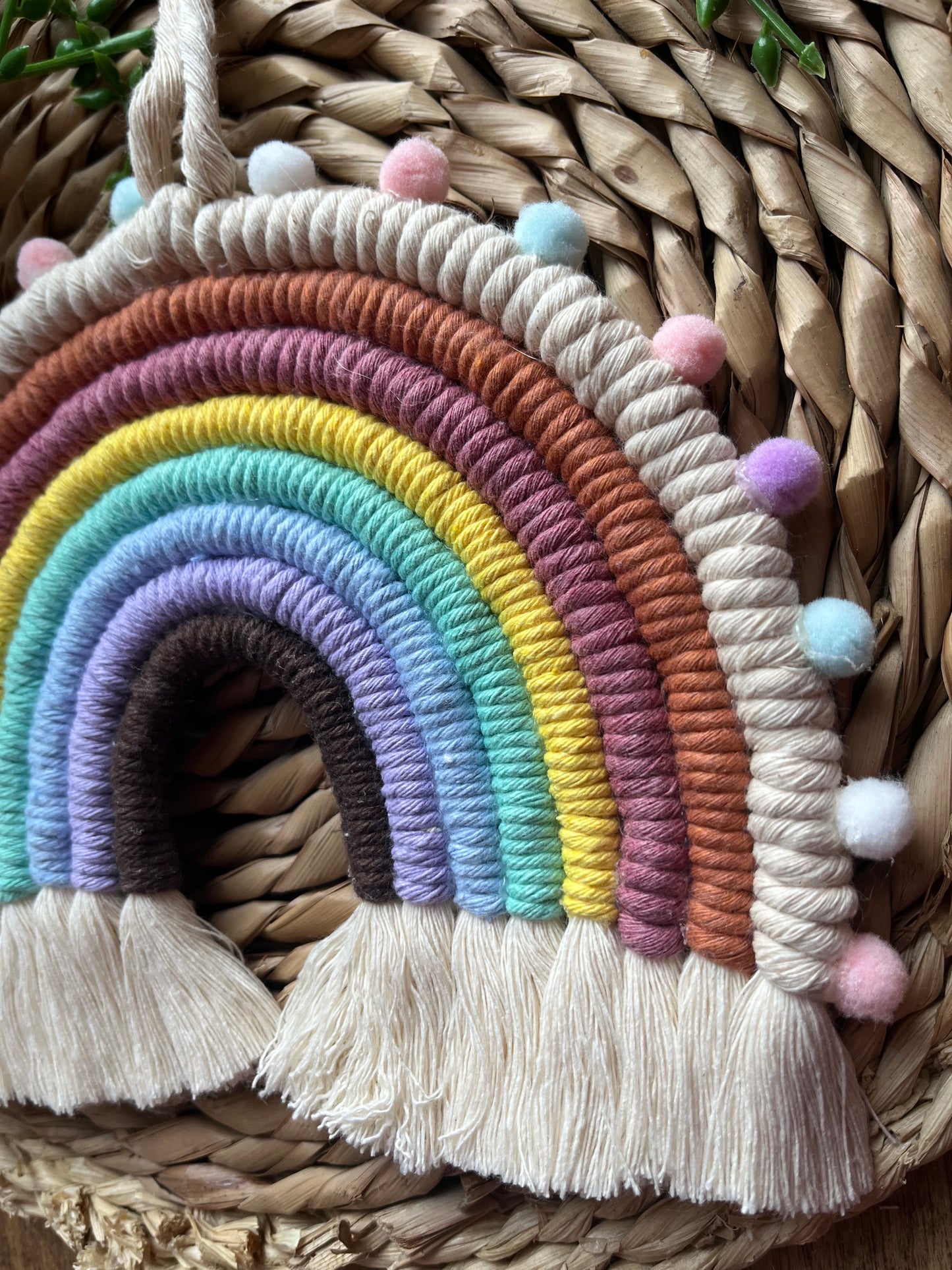 Handmade macrame rainbow, made using pastel shades of recycled cotton and finished with small pom poms.