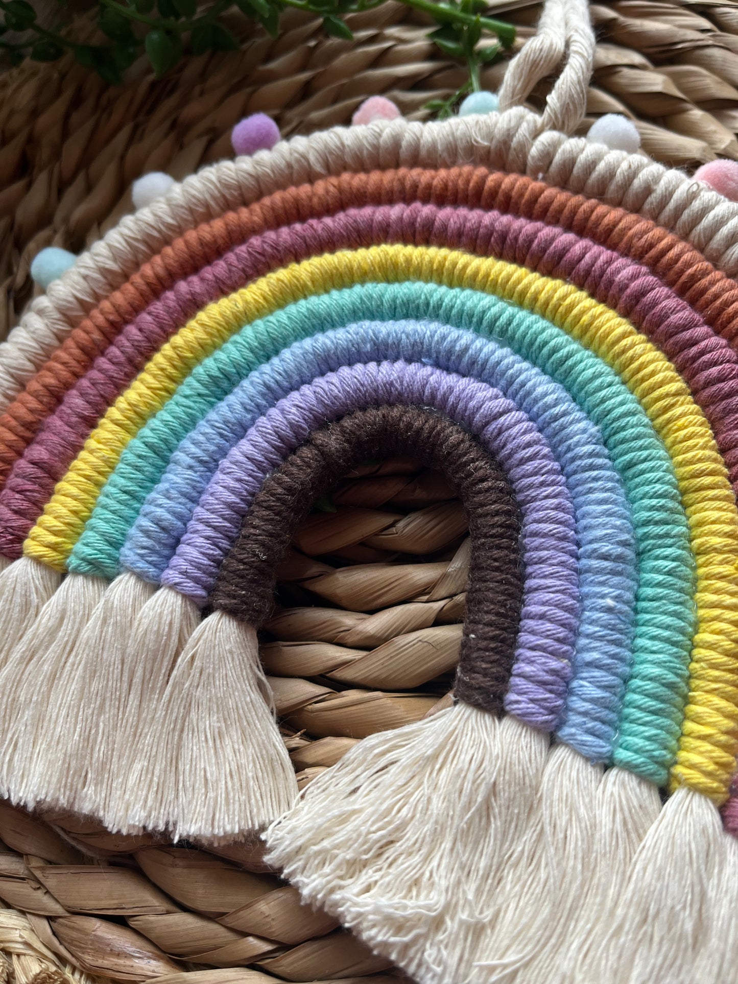 Handmade macrame rainbow made with pastel shades of recycled cotton and finished with small pastel coloured pom poms.