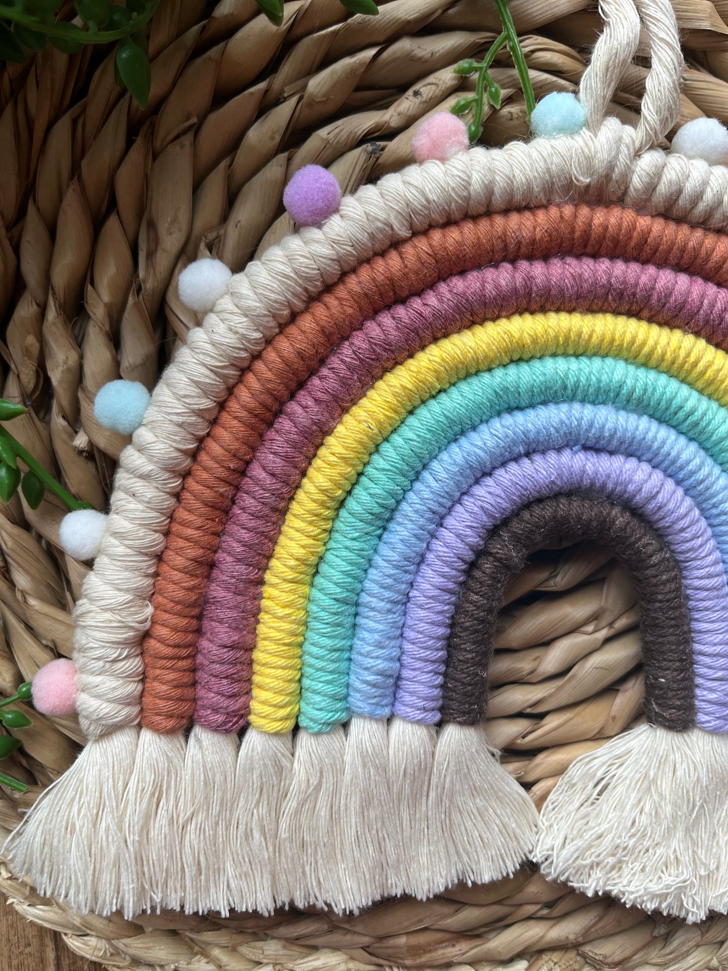 Handmade macrame rainbow made with pastel shades of recycled cotton and finished with small pom poms.