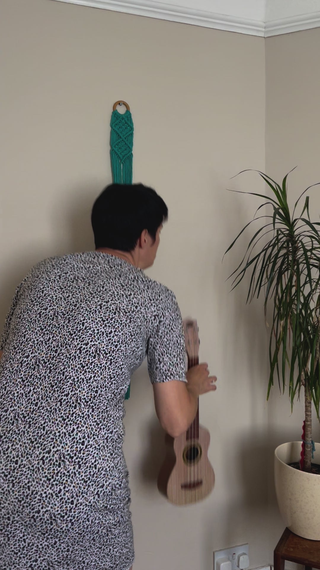video showing a ukulele being put in to a macrame wall hanger.