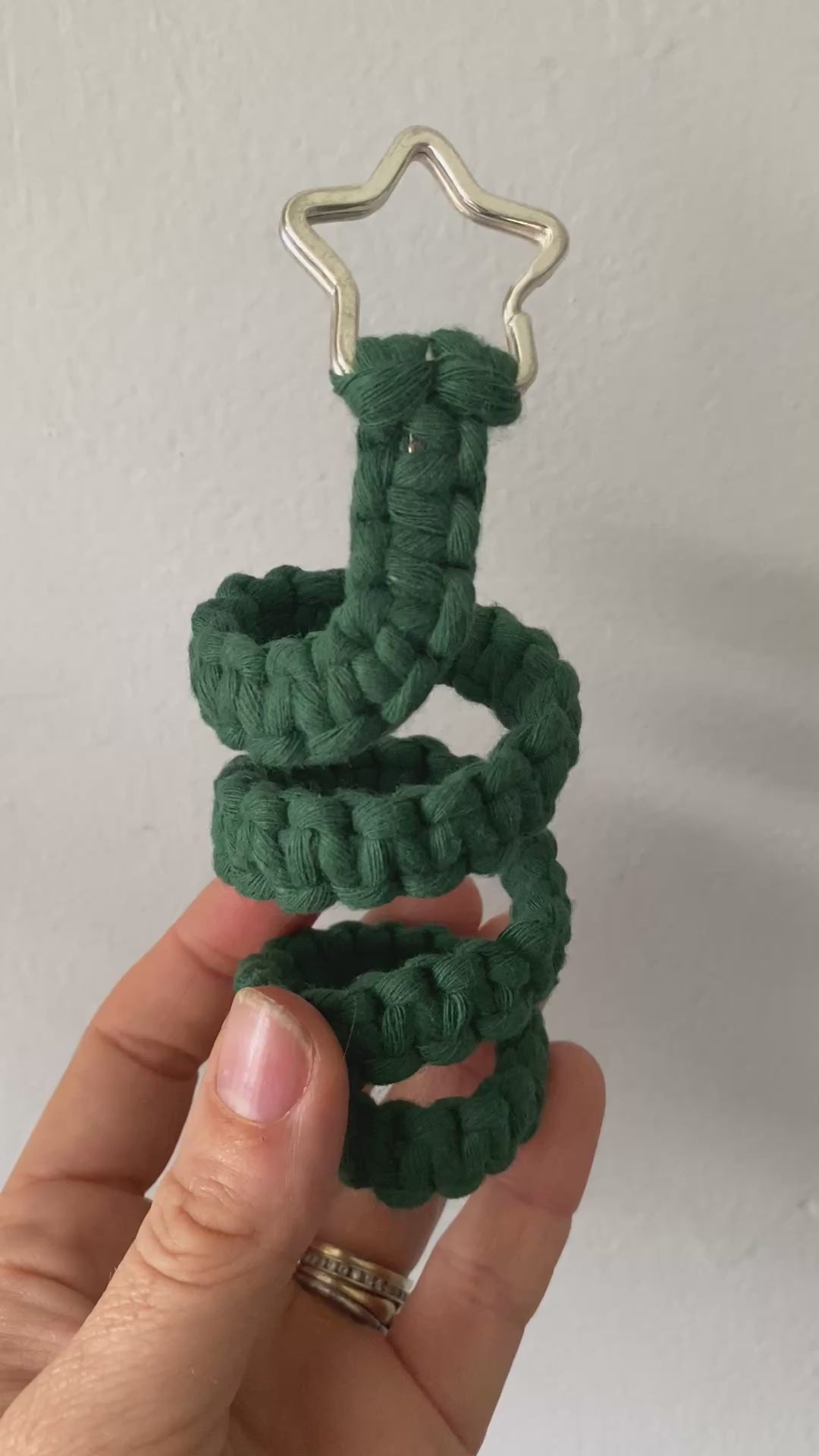 A video showing close up details of a freestanding spiral macrame christmas tree ornament made with green yarn and a silver star on top.