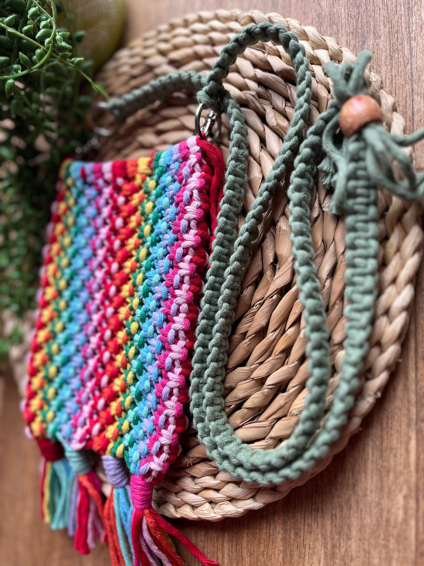 Colourful macrame bag with tassels and a long green strap, on a woven surface