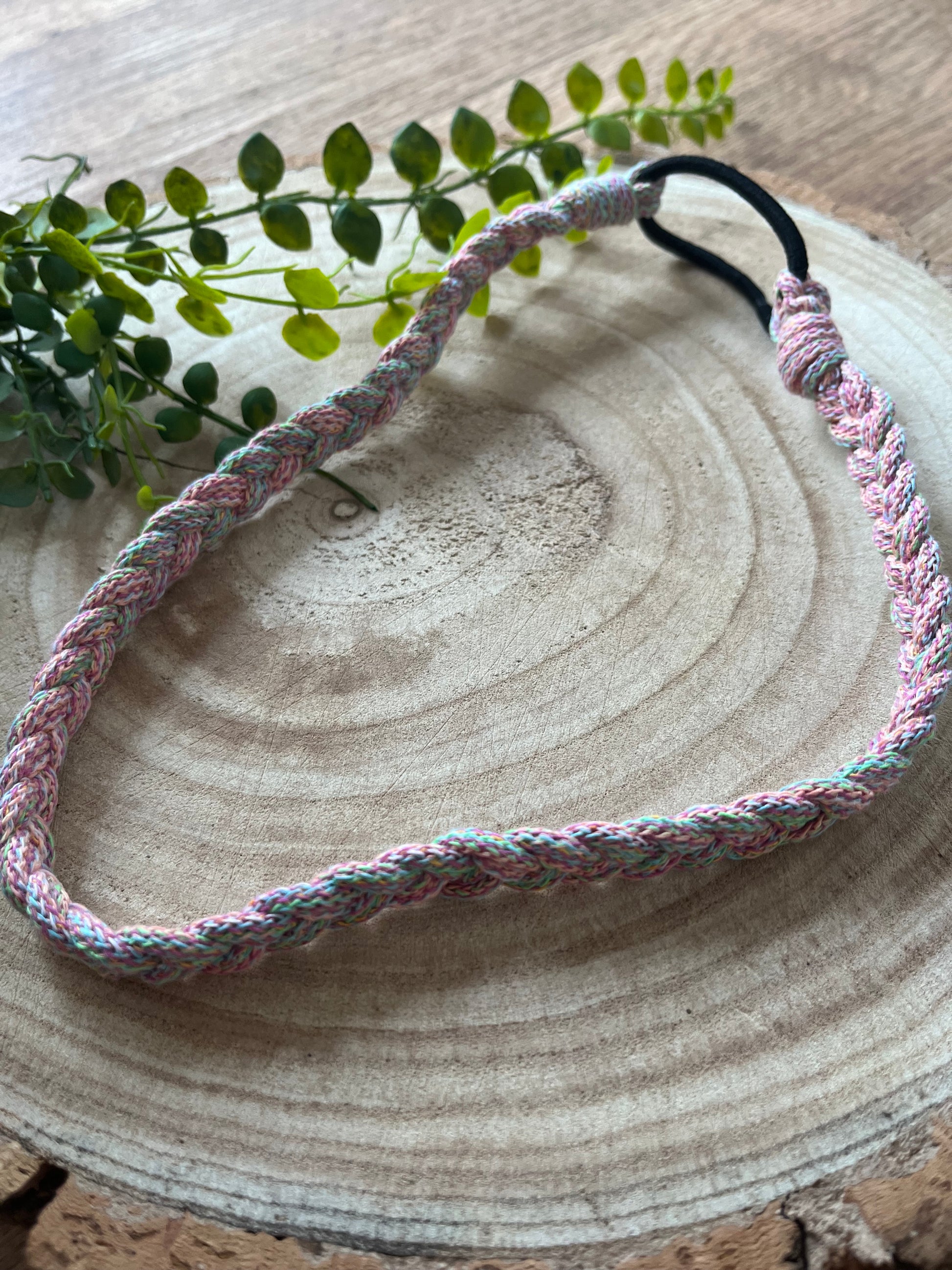 A multicoloured stretchy braided headband on a wooden board.