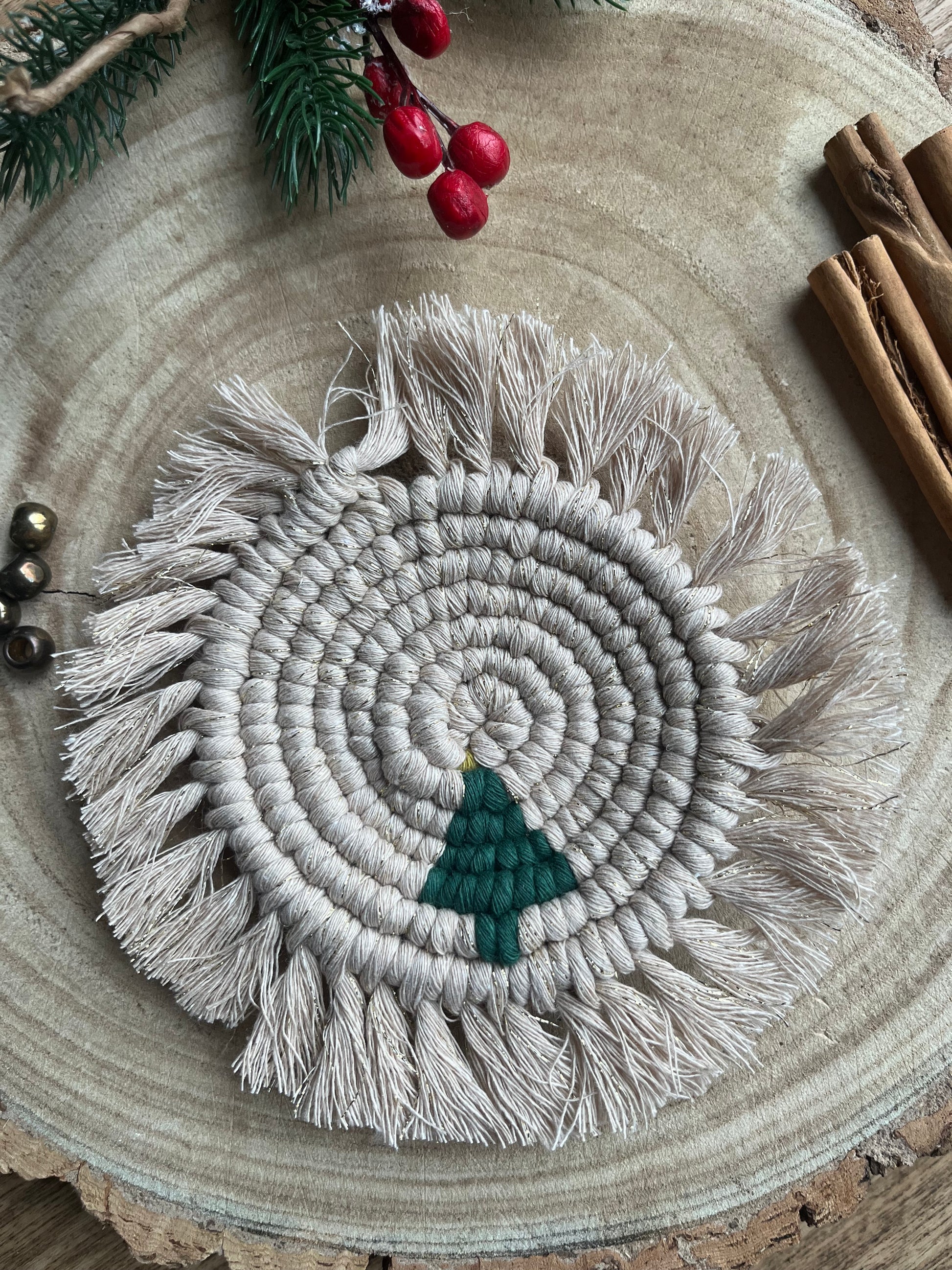 Round macrame coaster with a small christmas tree accent and fringed edge. Handmade with gold coloured recycled cotton yarn.